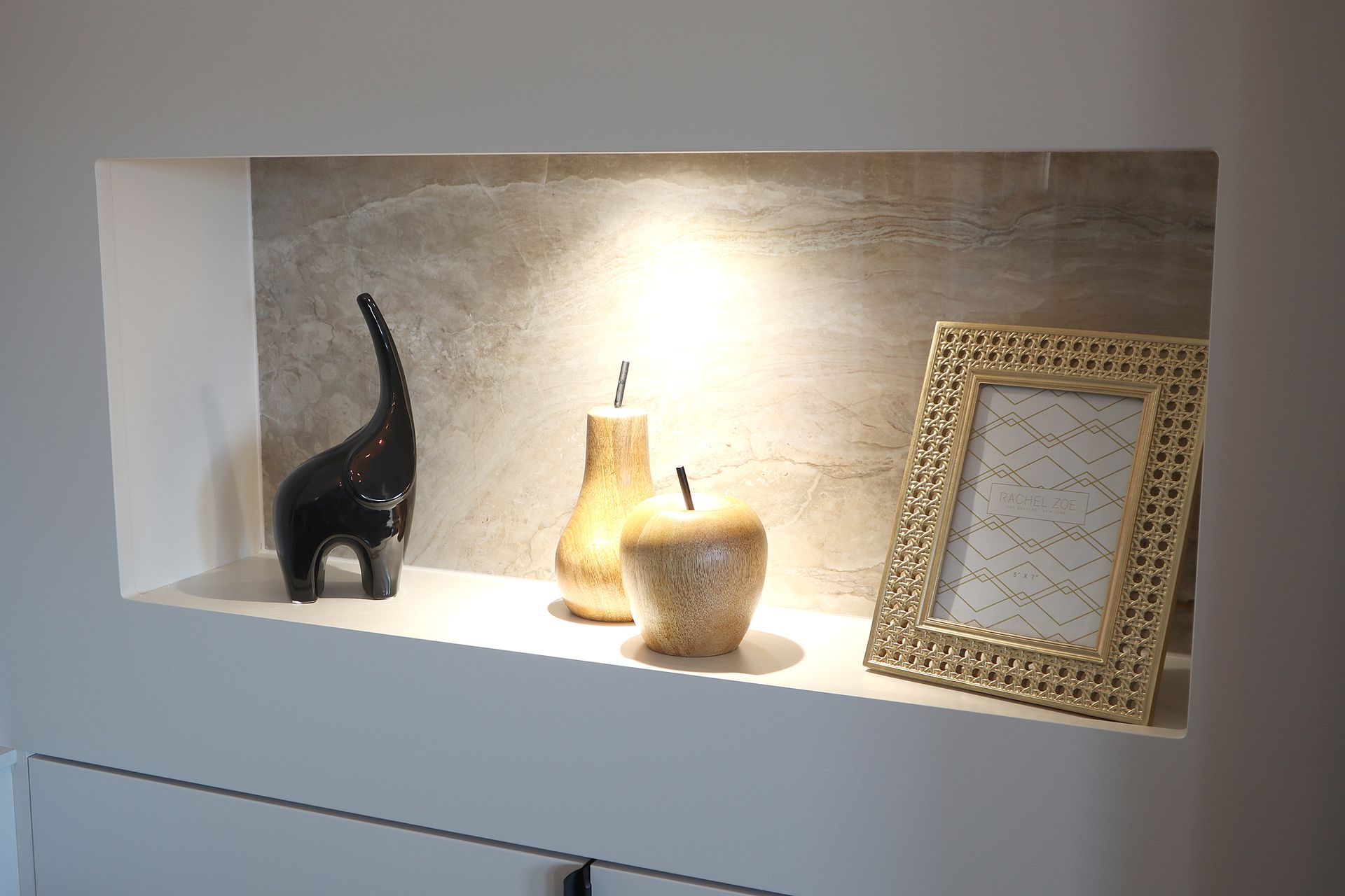 A shelf with a picture frame , a vase , and an elephant on it.