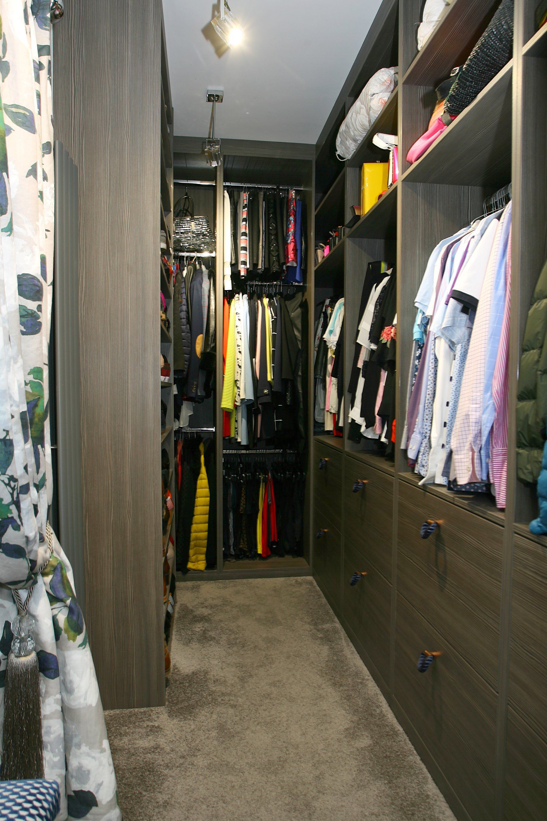 A walk in closet filled with lots of clothes and a chair.