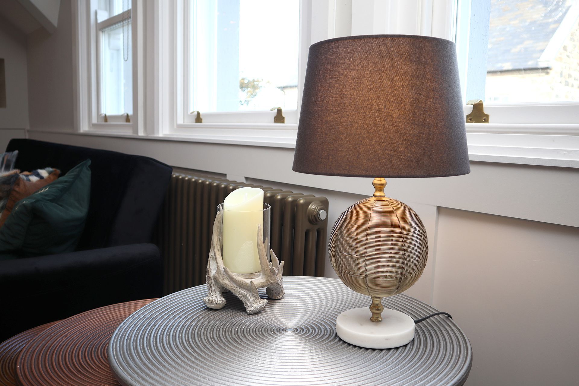 A lamp is sitting on a table next to a candle.