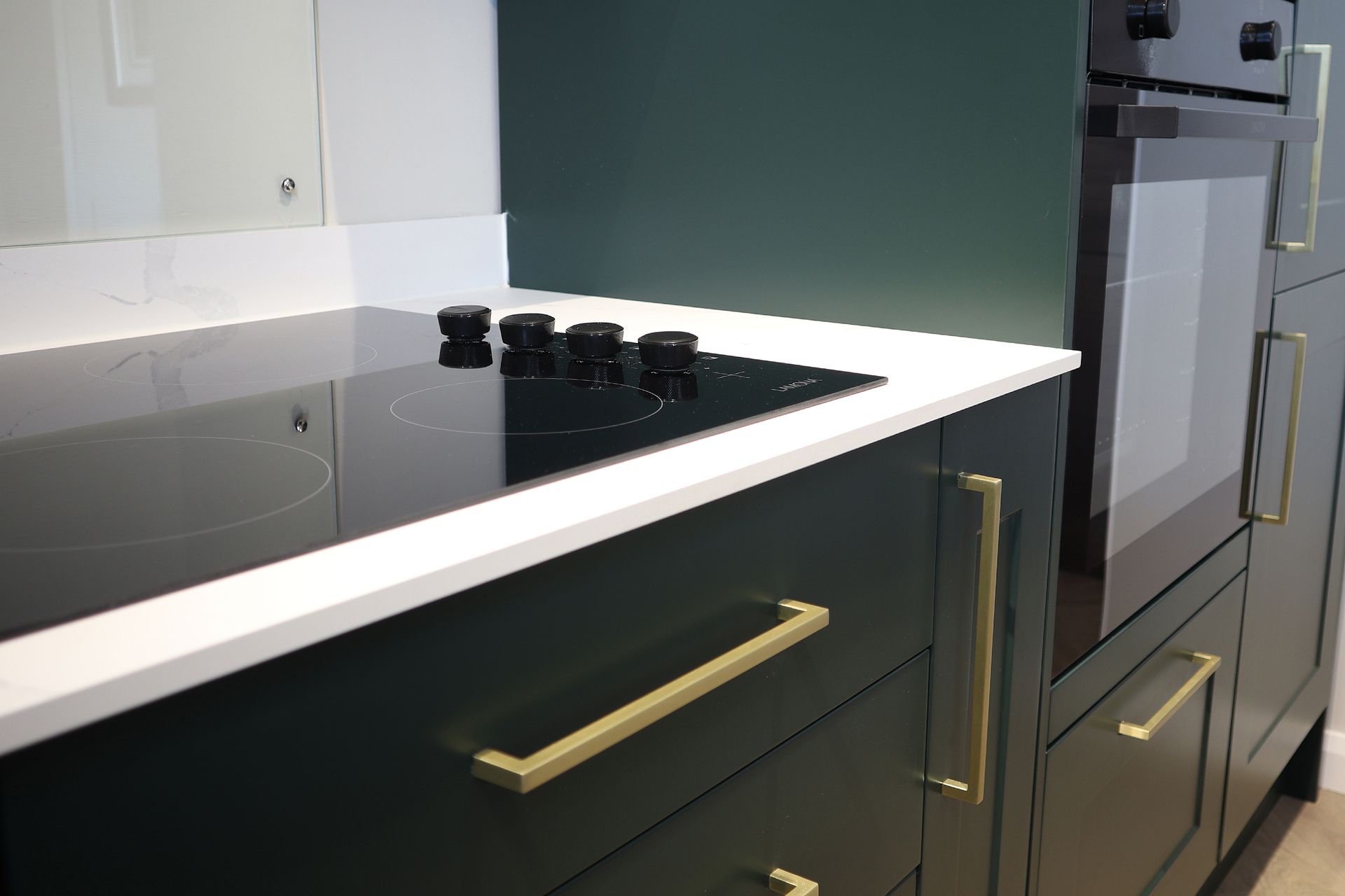 A kitchen with green cabinets and a black stove top oven