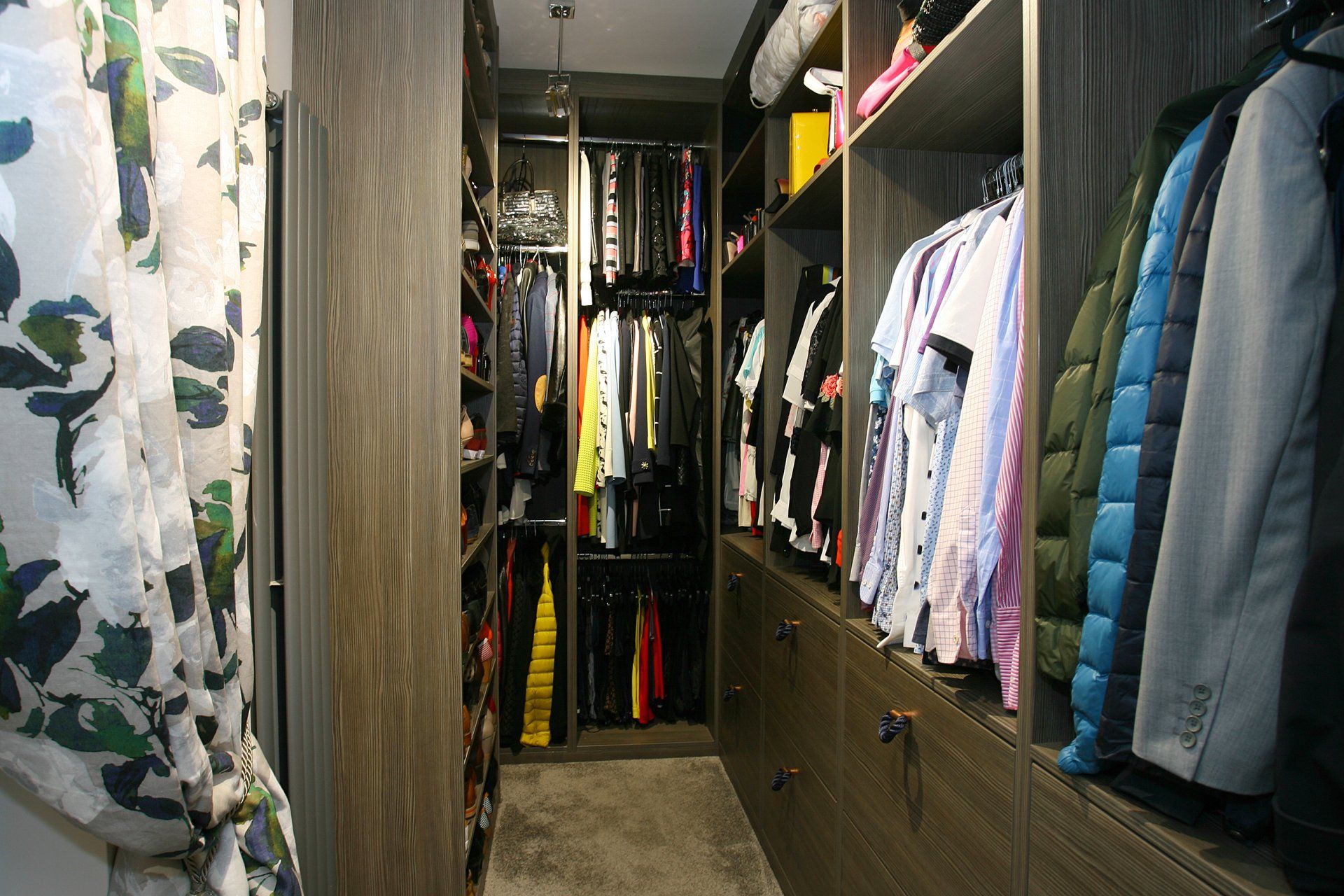 A walk in closet filled with lots of clothes and jackets.