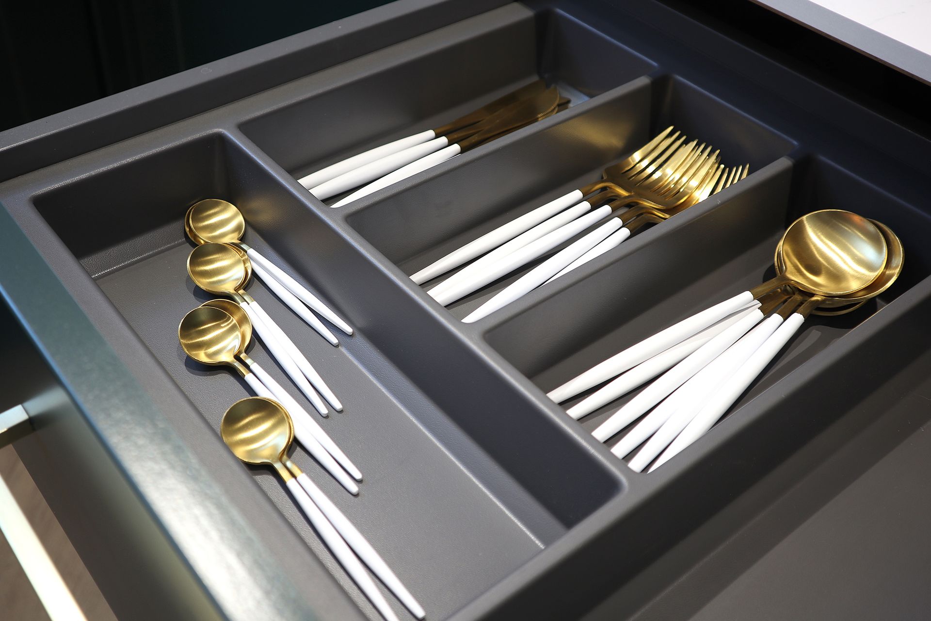 A silverware drawer filled with gold and white utensils