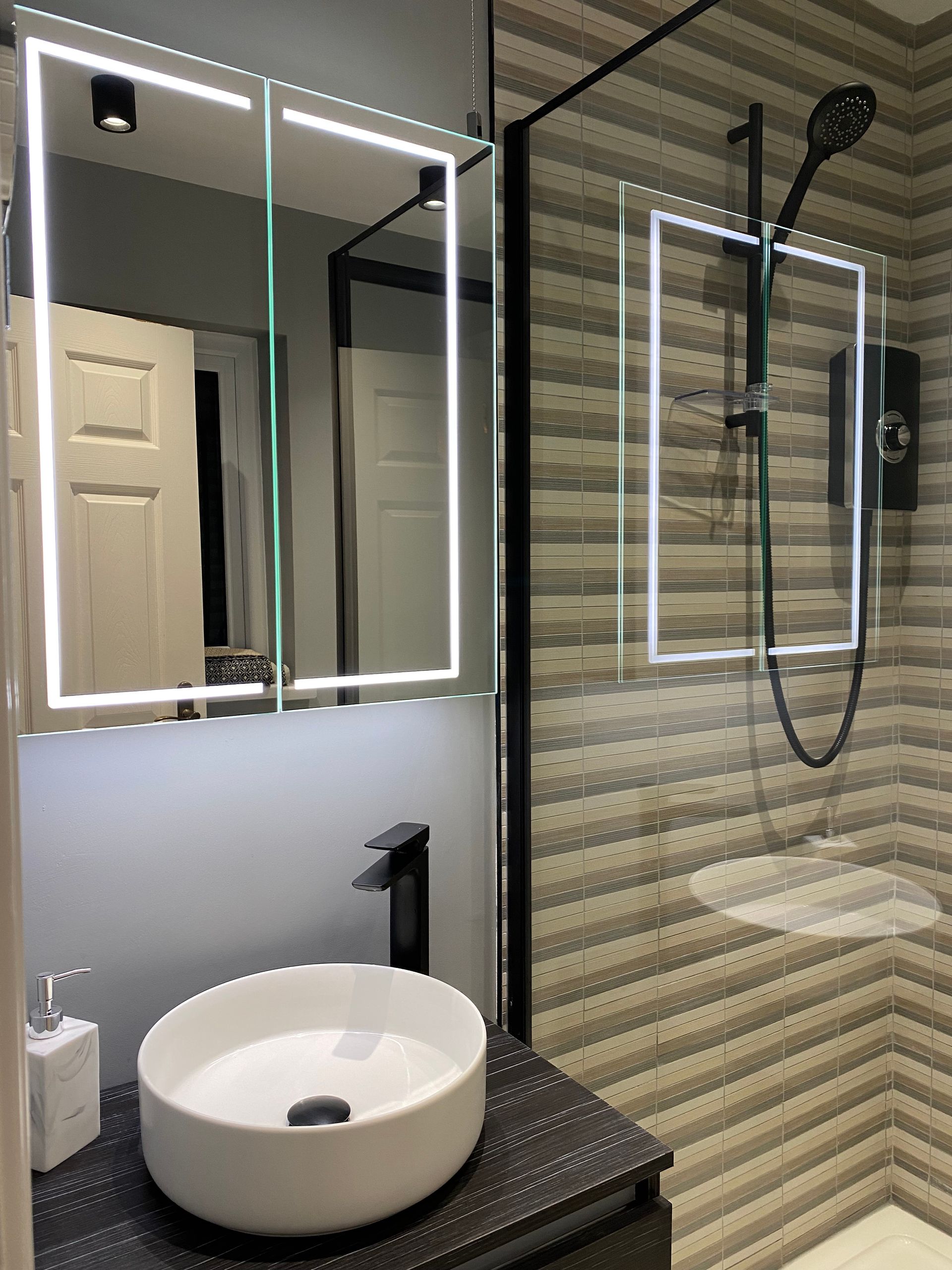 A bathroom with a sink , mirror and shower.