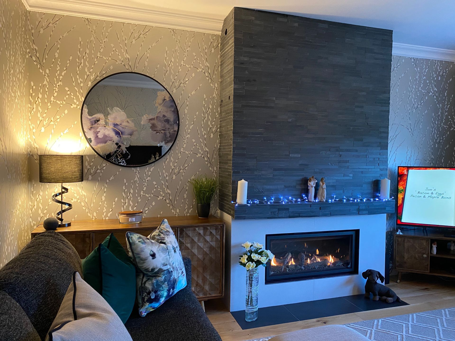 A living room with a fireplace , couch , television and mirror.