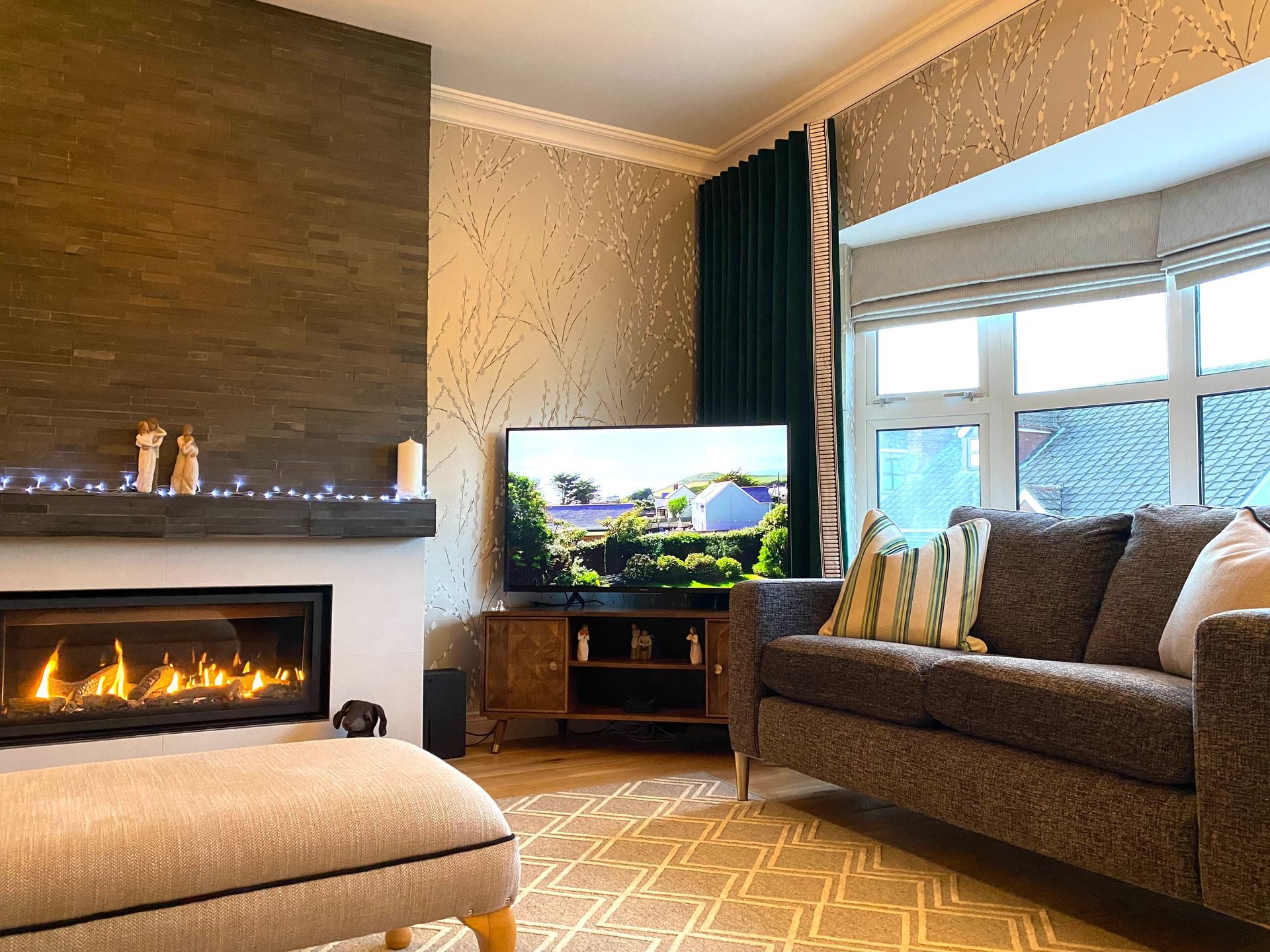 A living room with a couch , ottoman , fireplace and television.