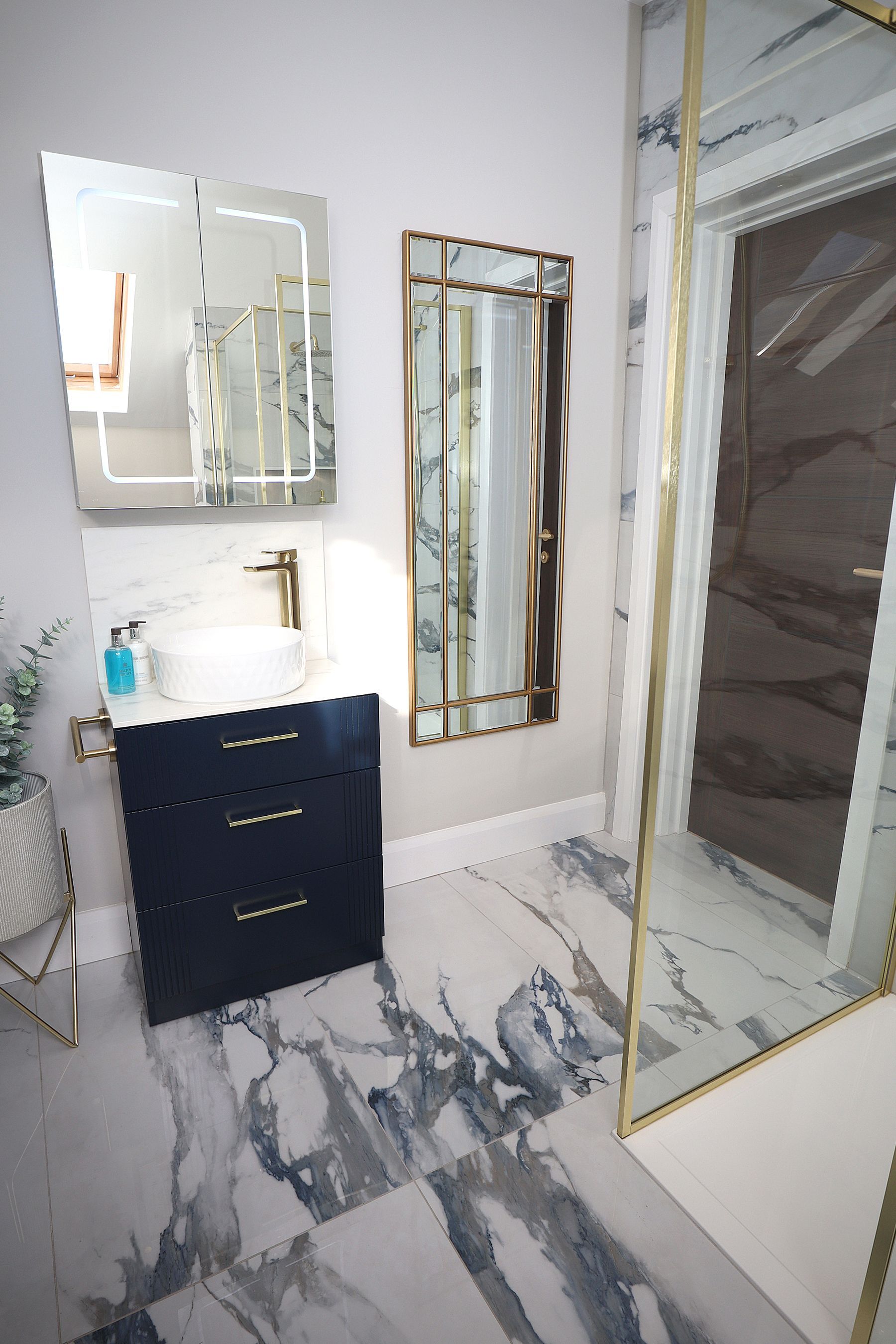 A bathroom with a sink , mirror , and walk in shower.