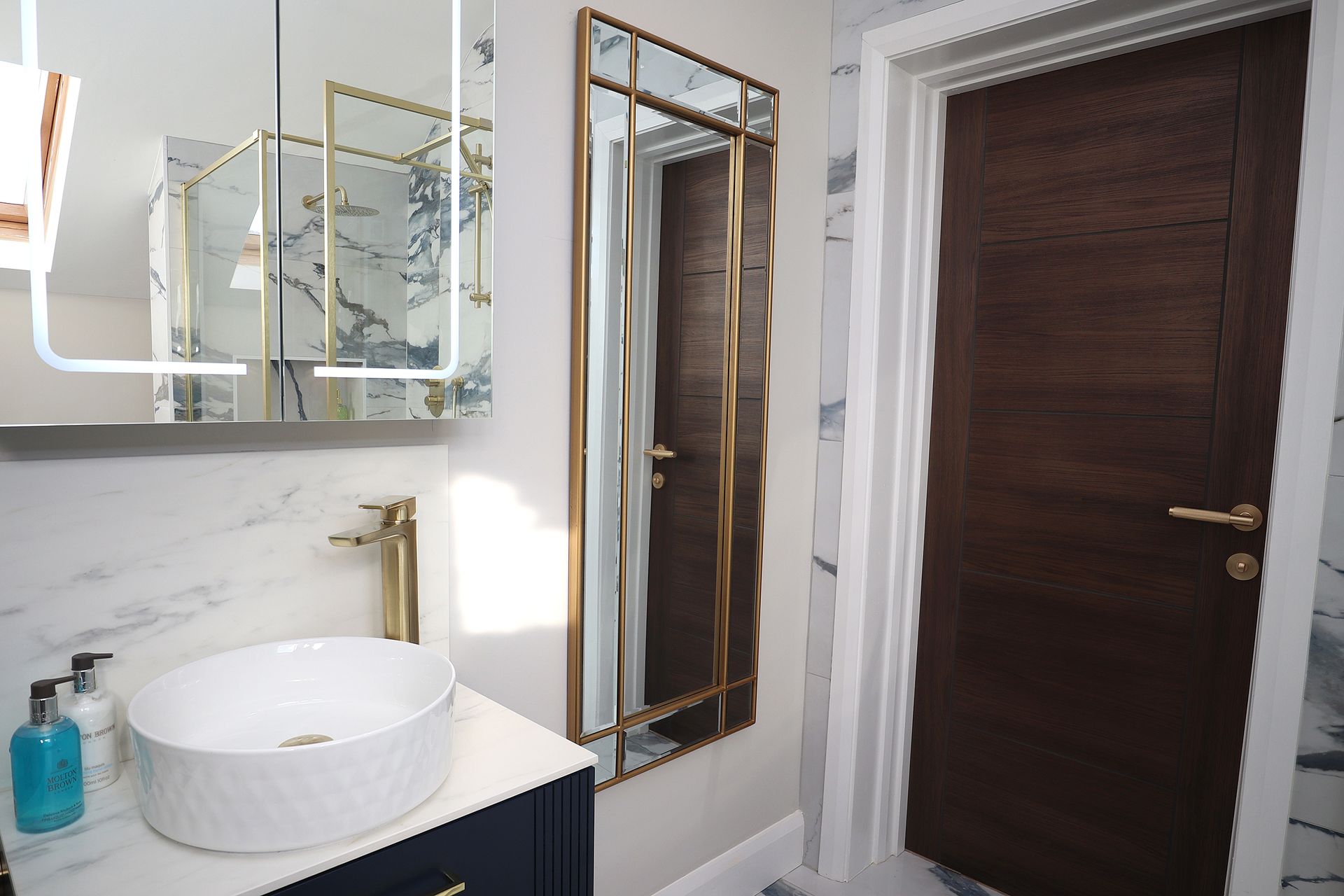 A bathroom with a sink , mirror and door.