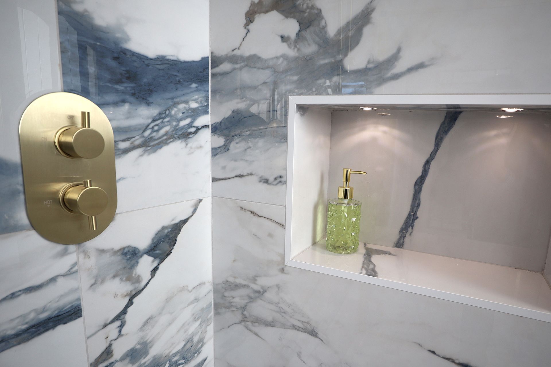 There is a soap dispenser in the corner of the bathroom.