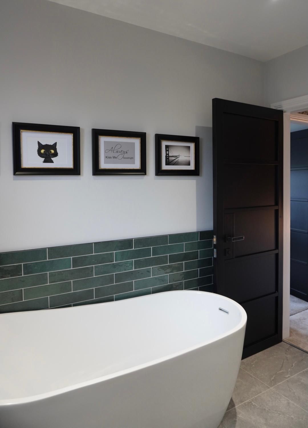 A bathroom with a bathtub and a black door