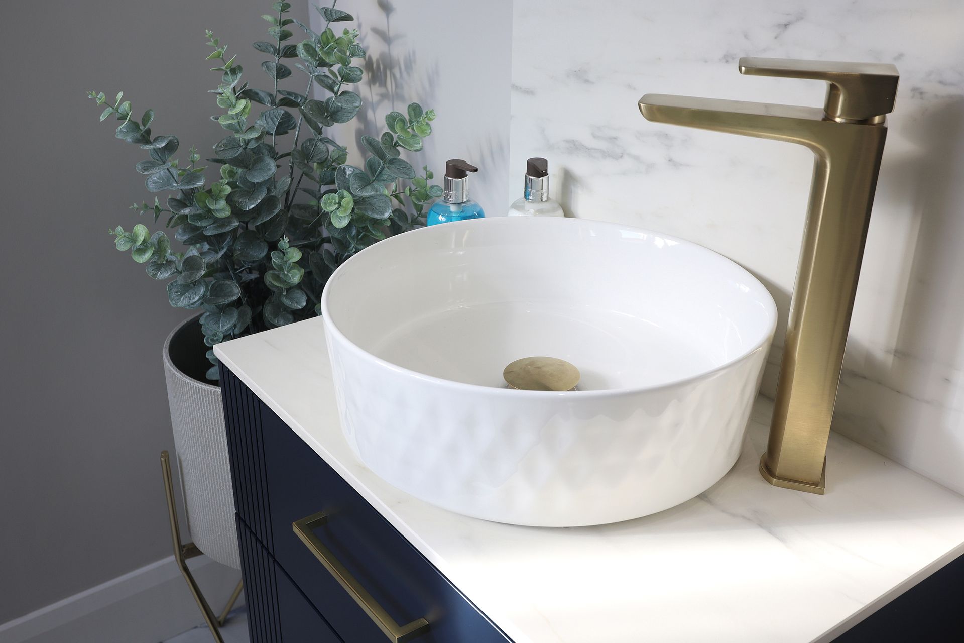 A white sink with a gold faucet is on a counter in a bathroom.