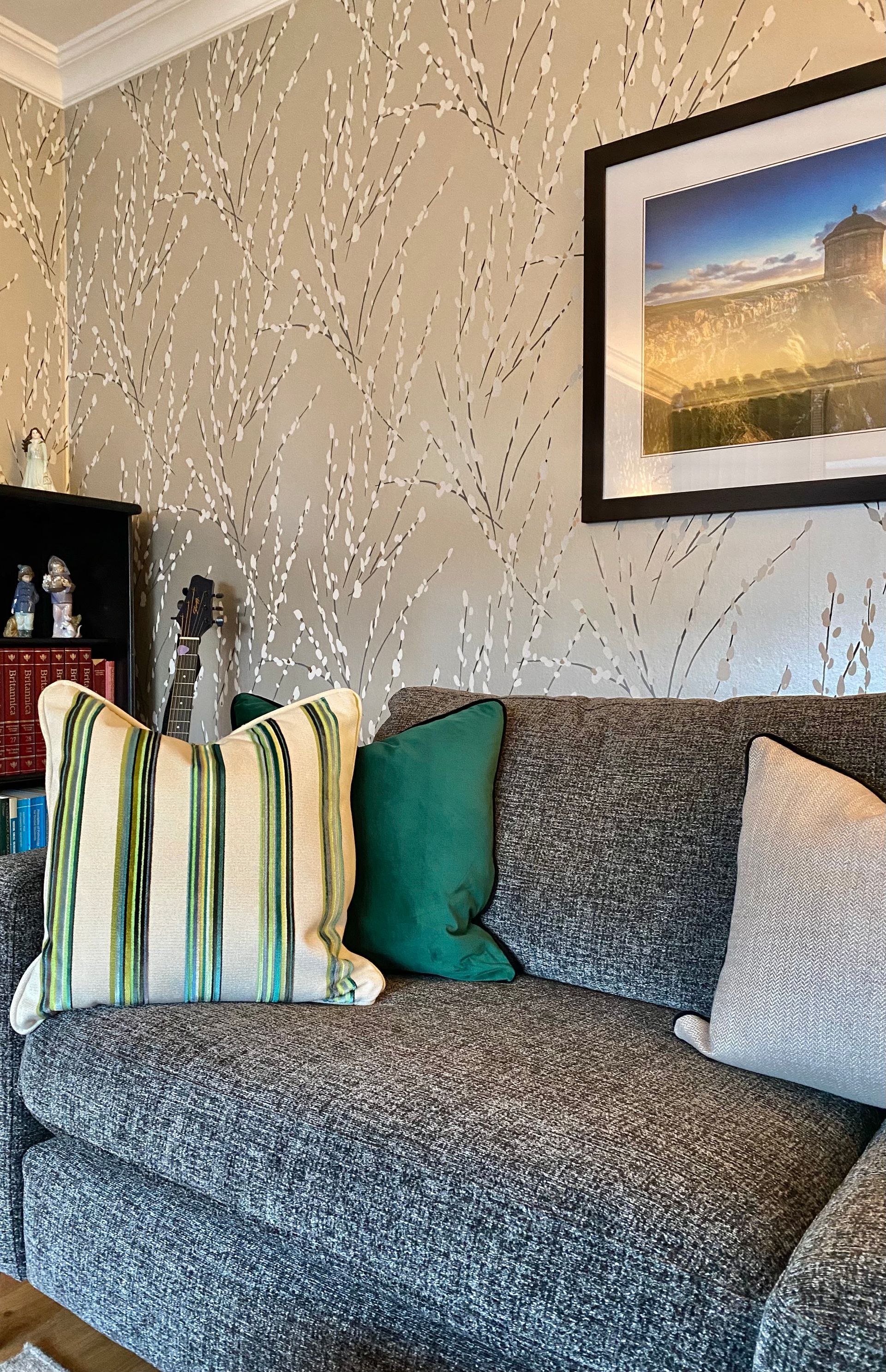 A living room with a couch and pillows and a picture on the wall.
