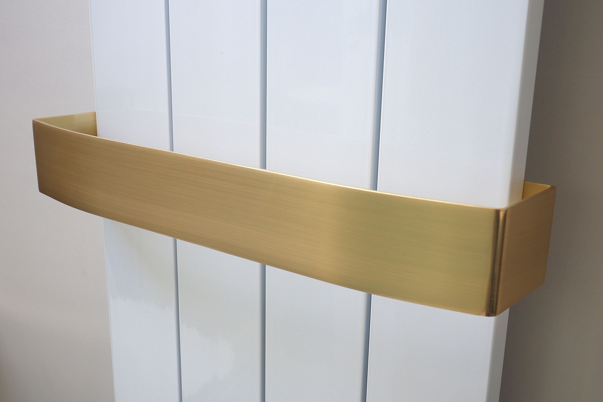 A gold towel rack is attached to a white radiator.