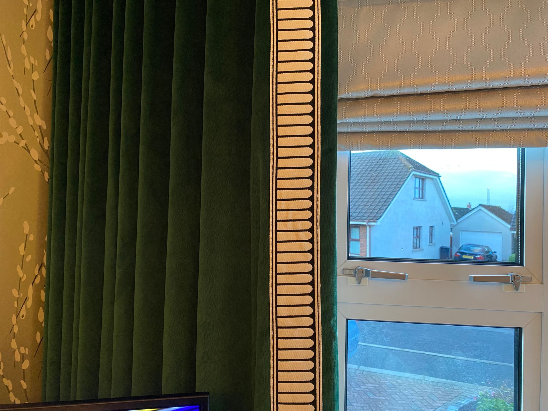 A living room with green curtains and a large mirror.