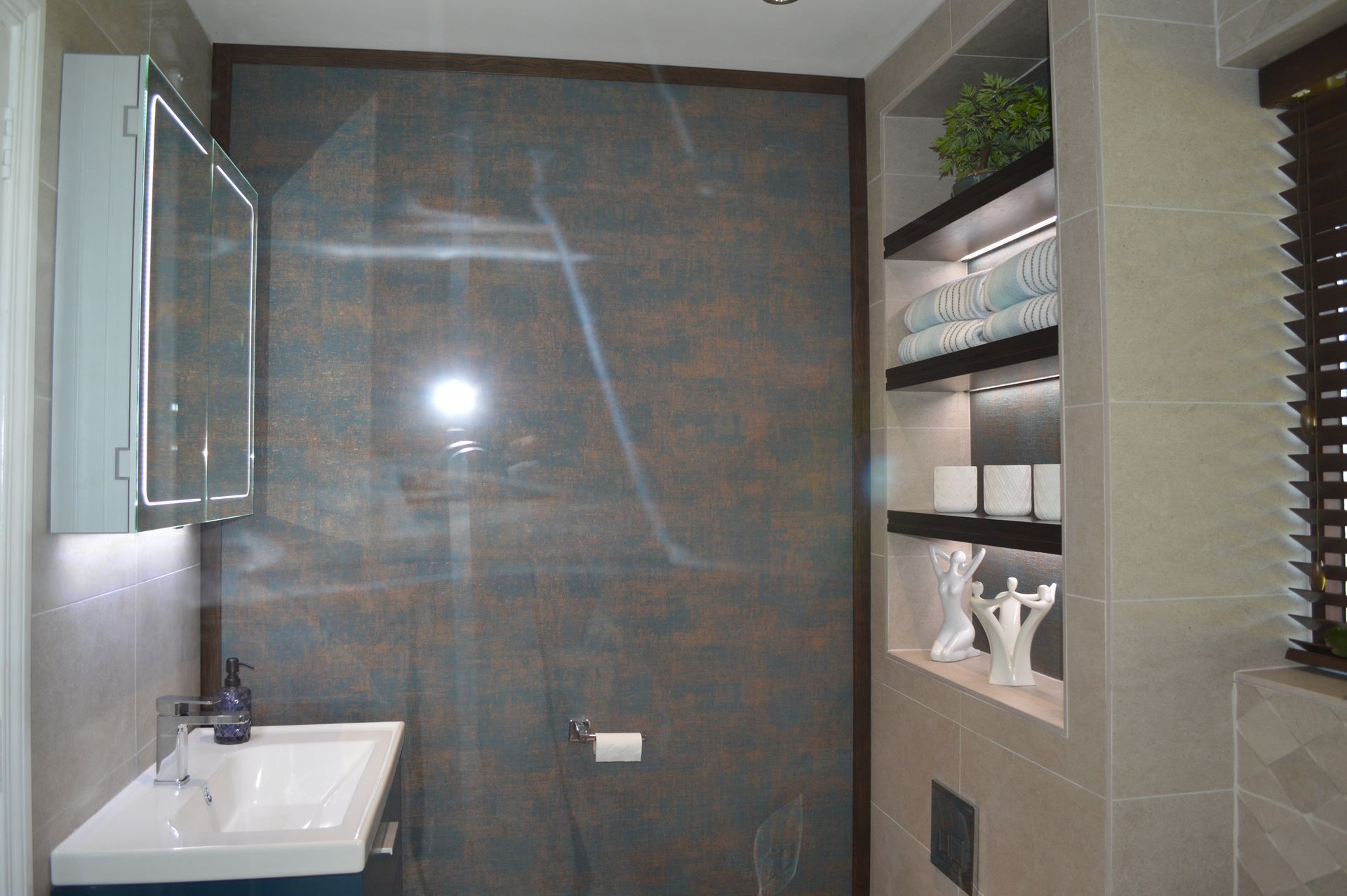 A bathroom with a sink , mirror , shelves and a walk in shower.