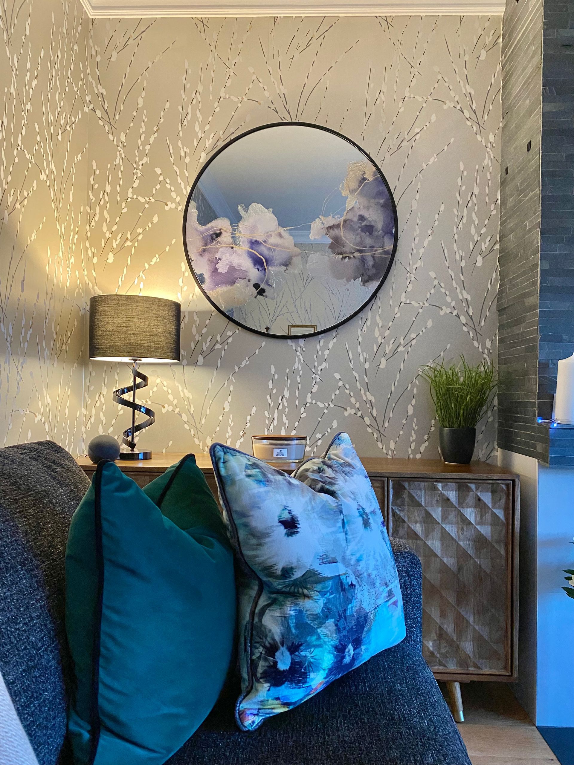 A living room with a couch and pillows and a mirror on the wall.