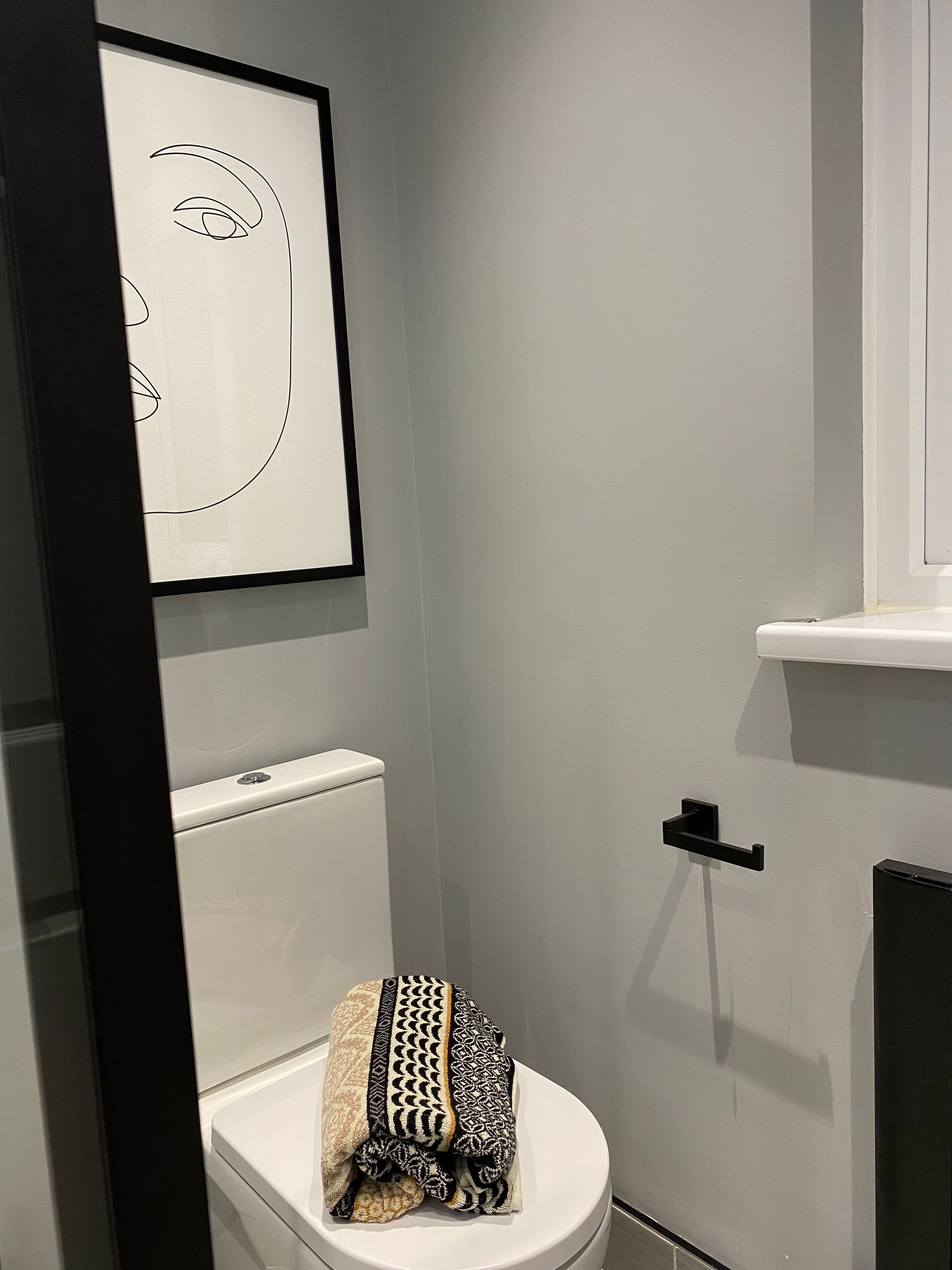 A bathroom with a toilet and a picture on the wall.