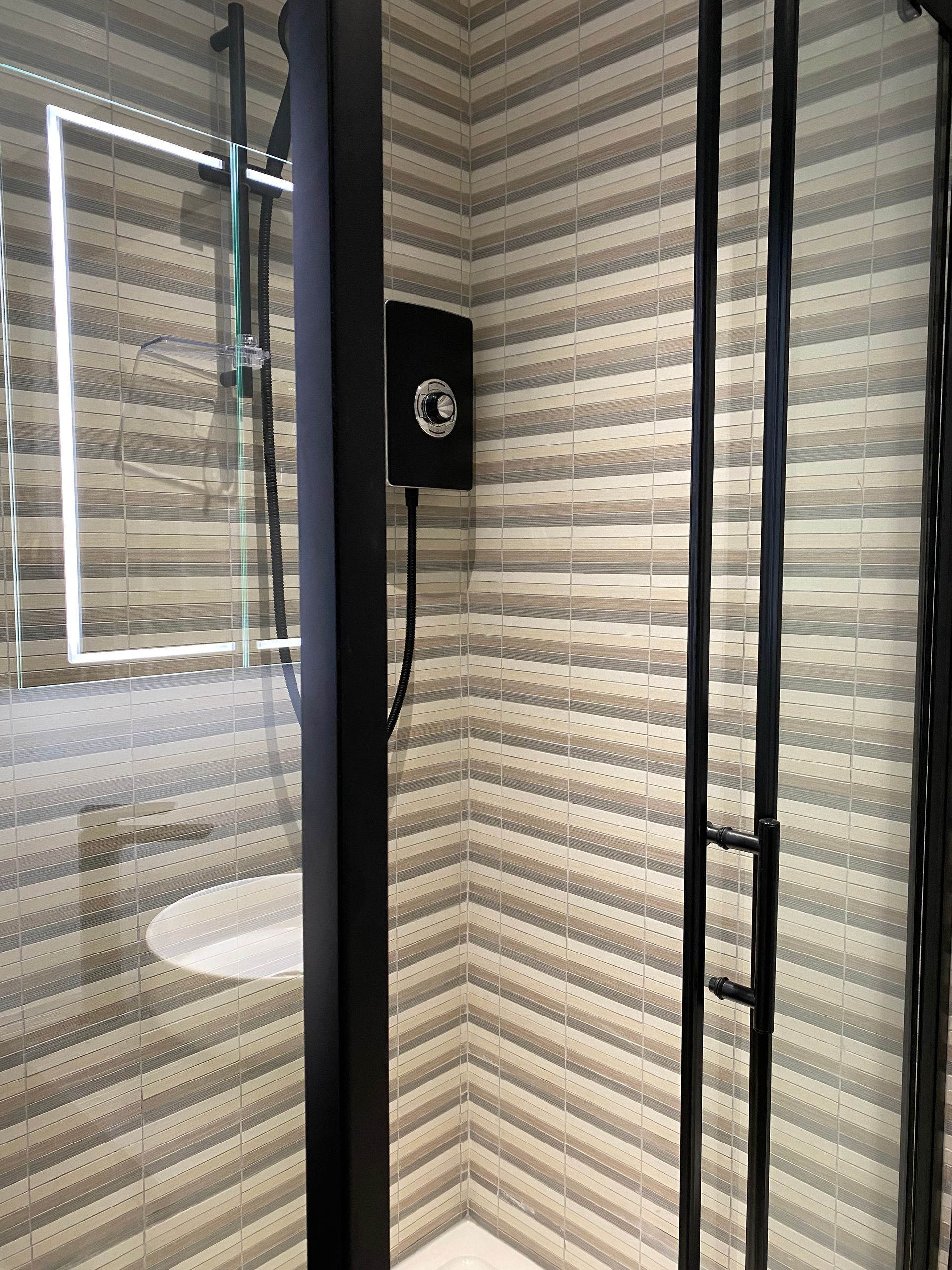 A bathroom with a shower , sink and mirror.