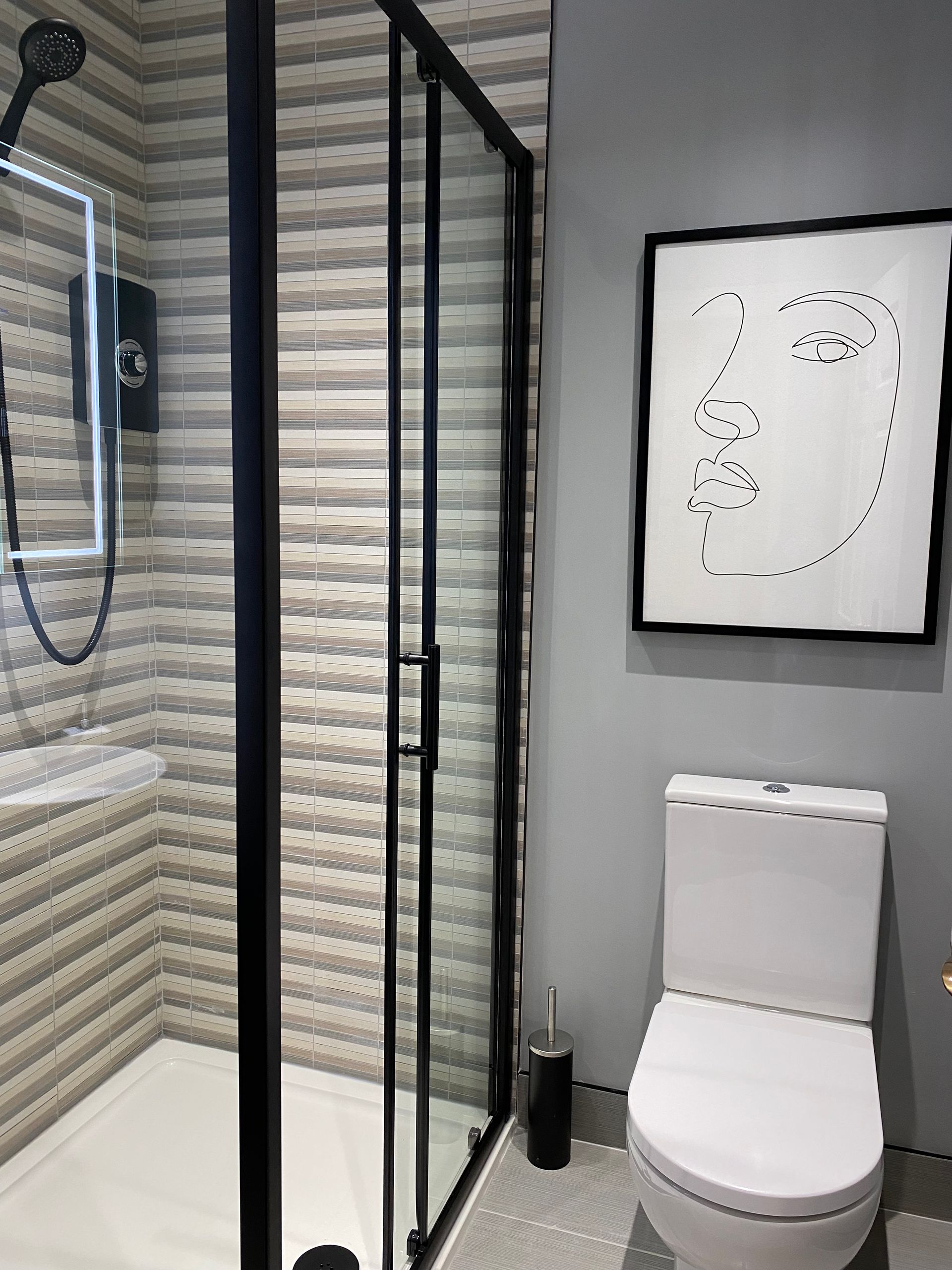 A bathroom with a toilet , shower , and picture on the wall.