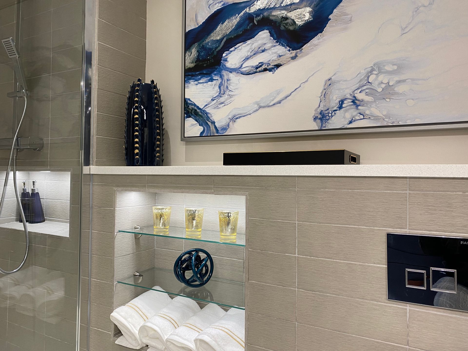 A bathroom with a painting on the wall above the shower.