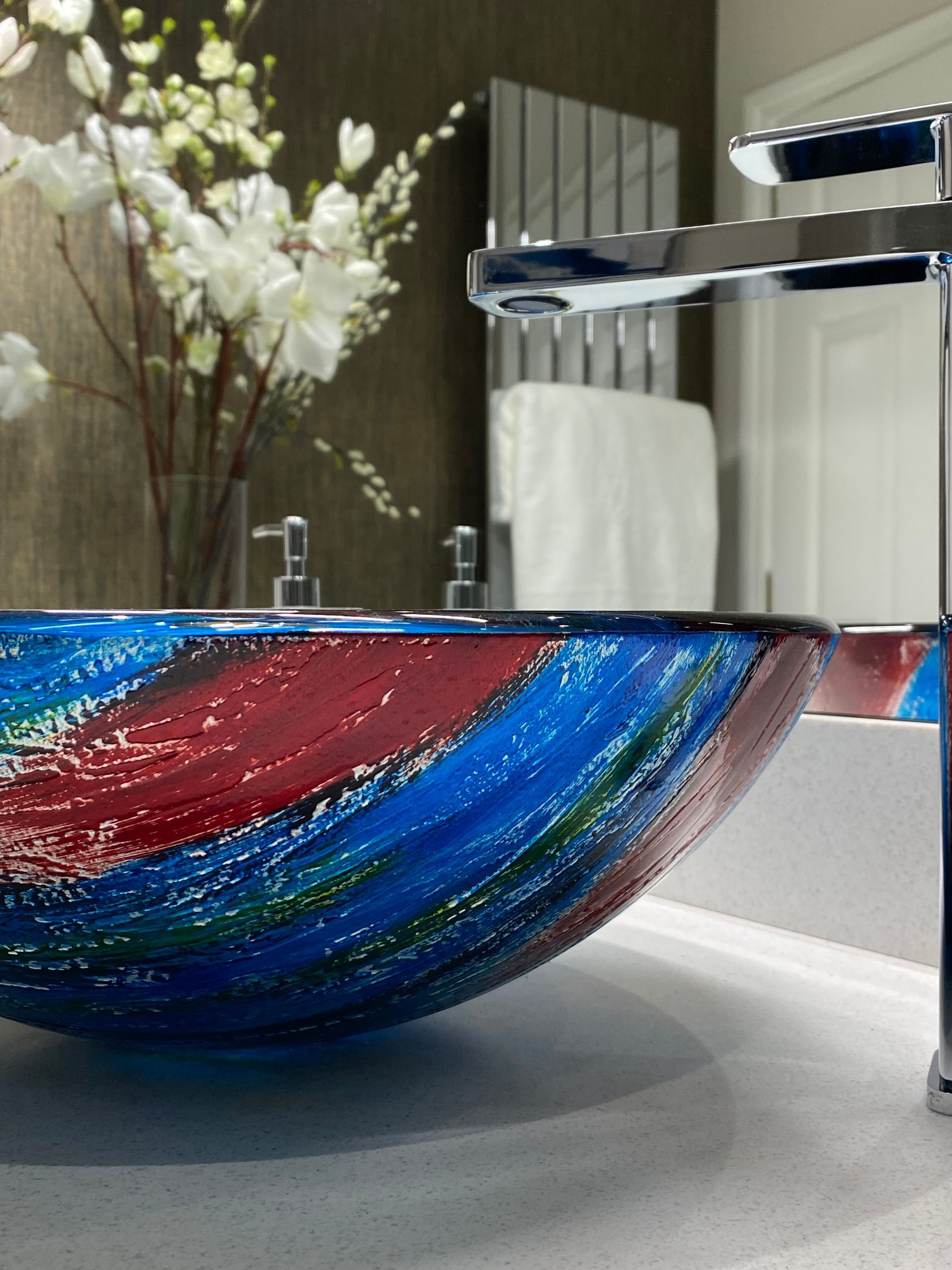 A bathroom with a colorful sink and a faucet