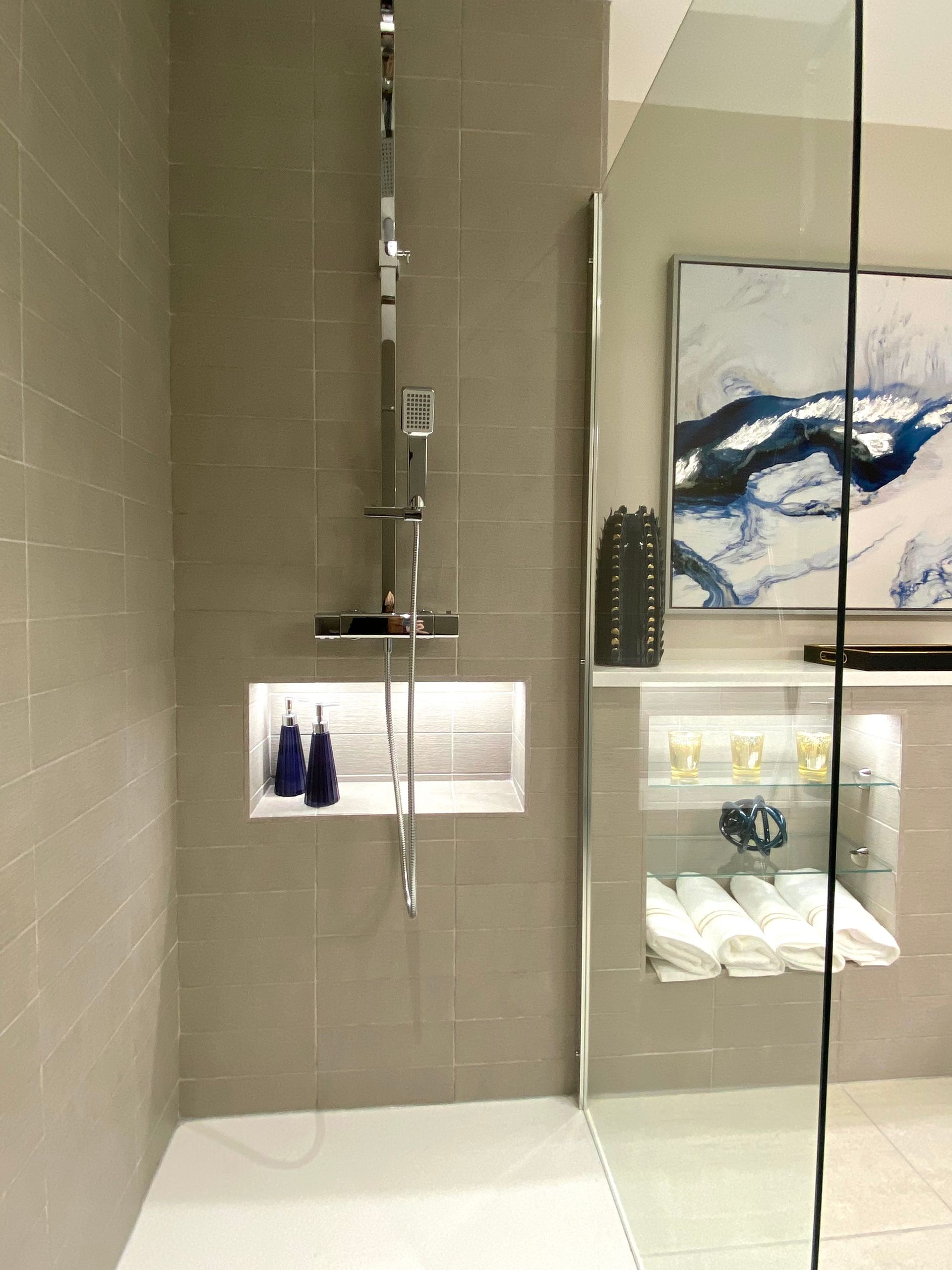 A bathroom with a walk in shower and a painting on the wall