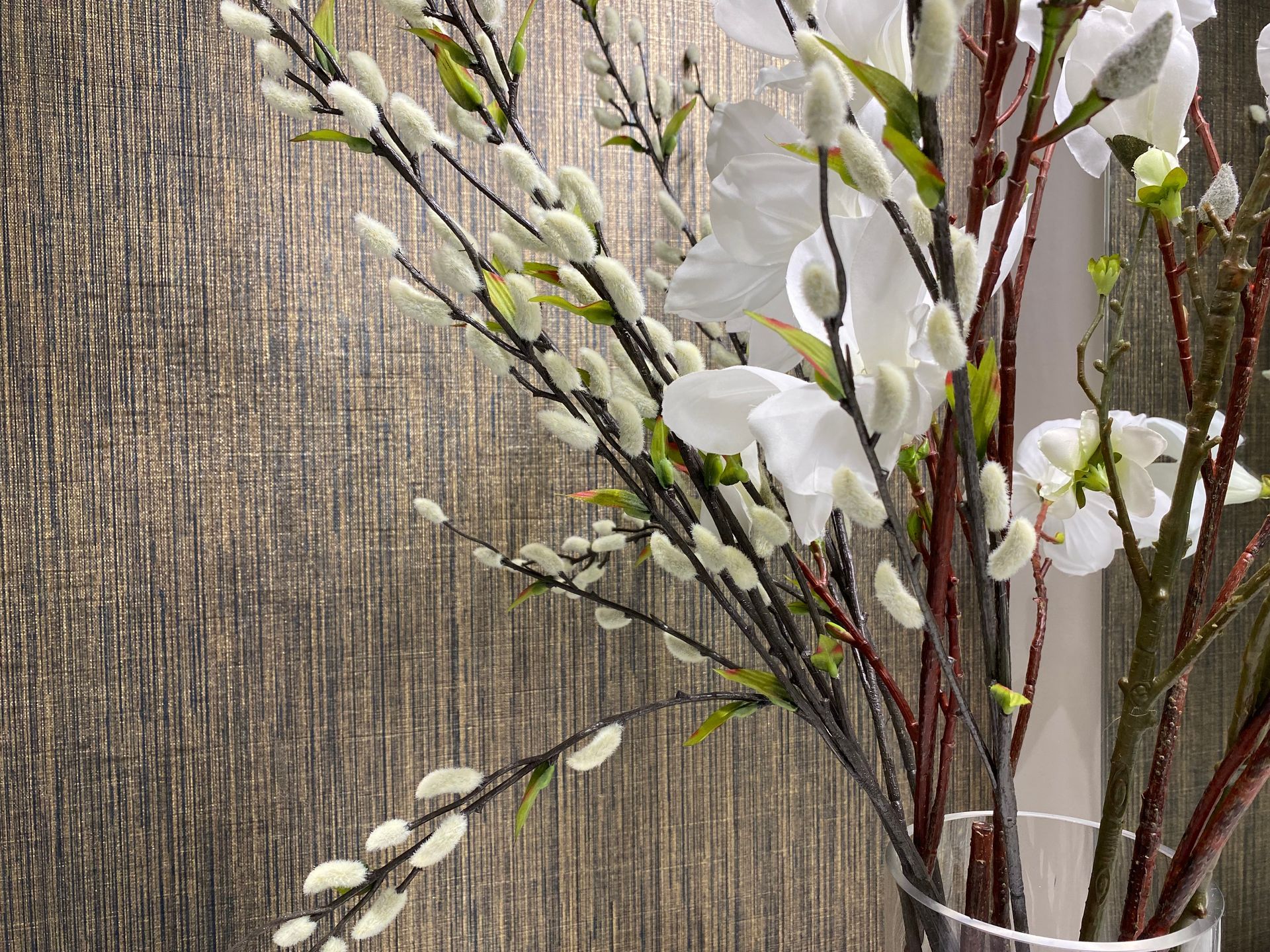A vase filled with white flowers and branches is sitting on a table.