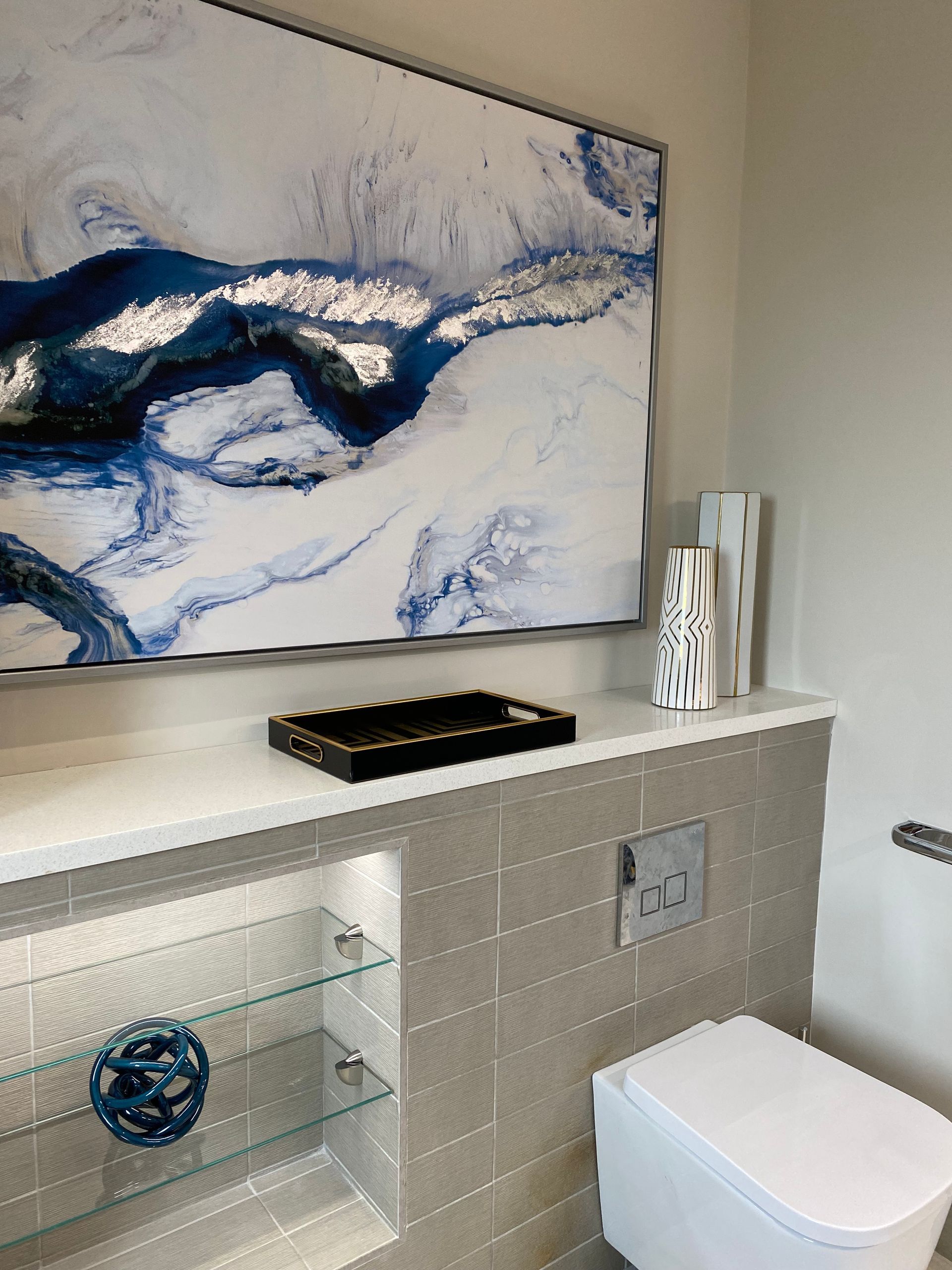 A bathroom with a toilet and a large painting on the wall.