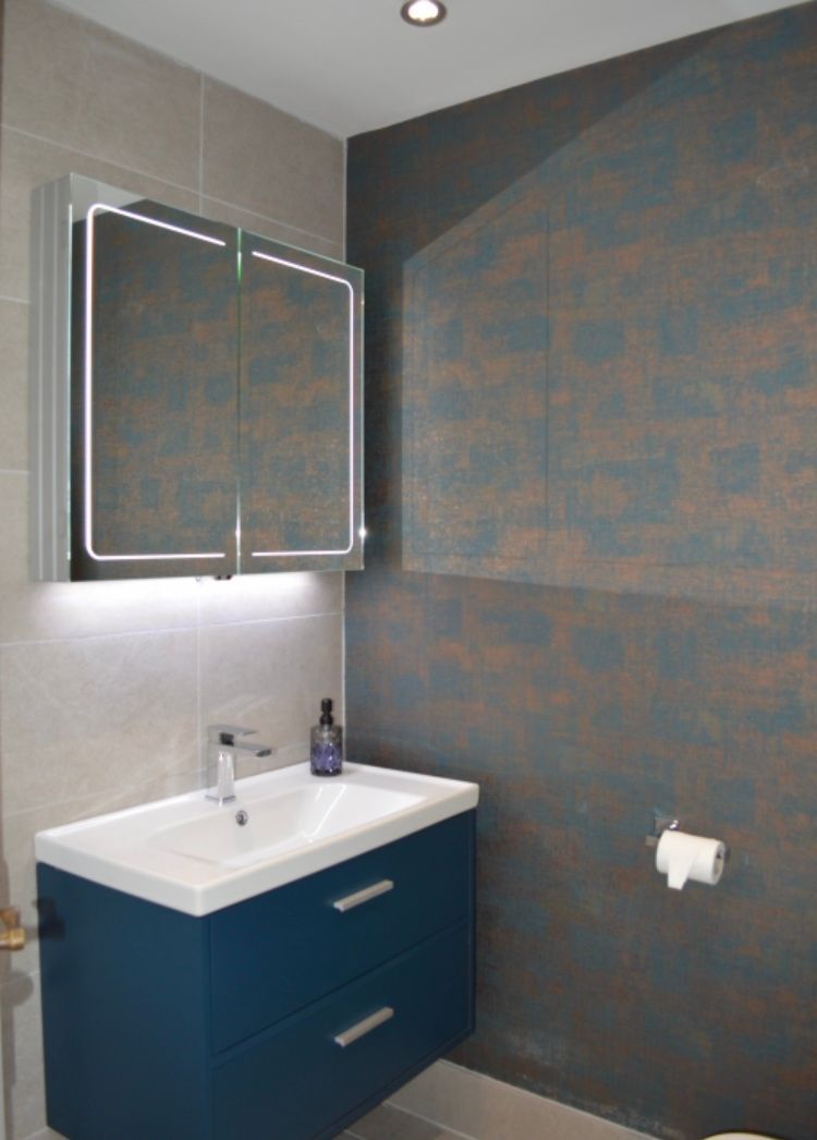 A bathroom with a sink , mirror and toilet paper.