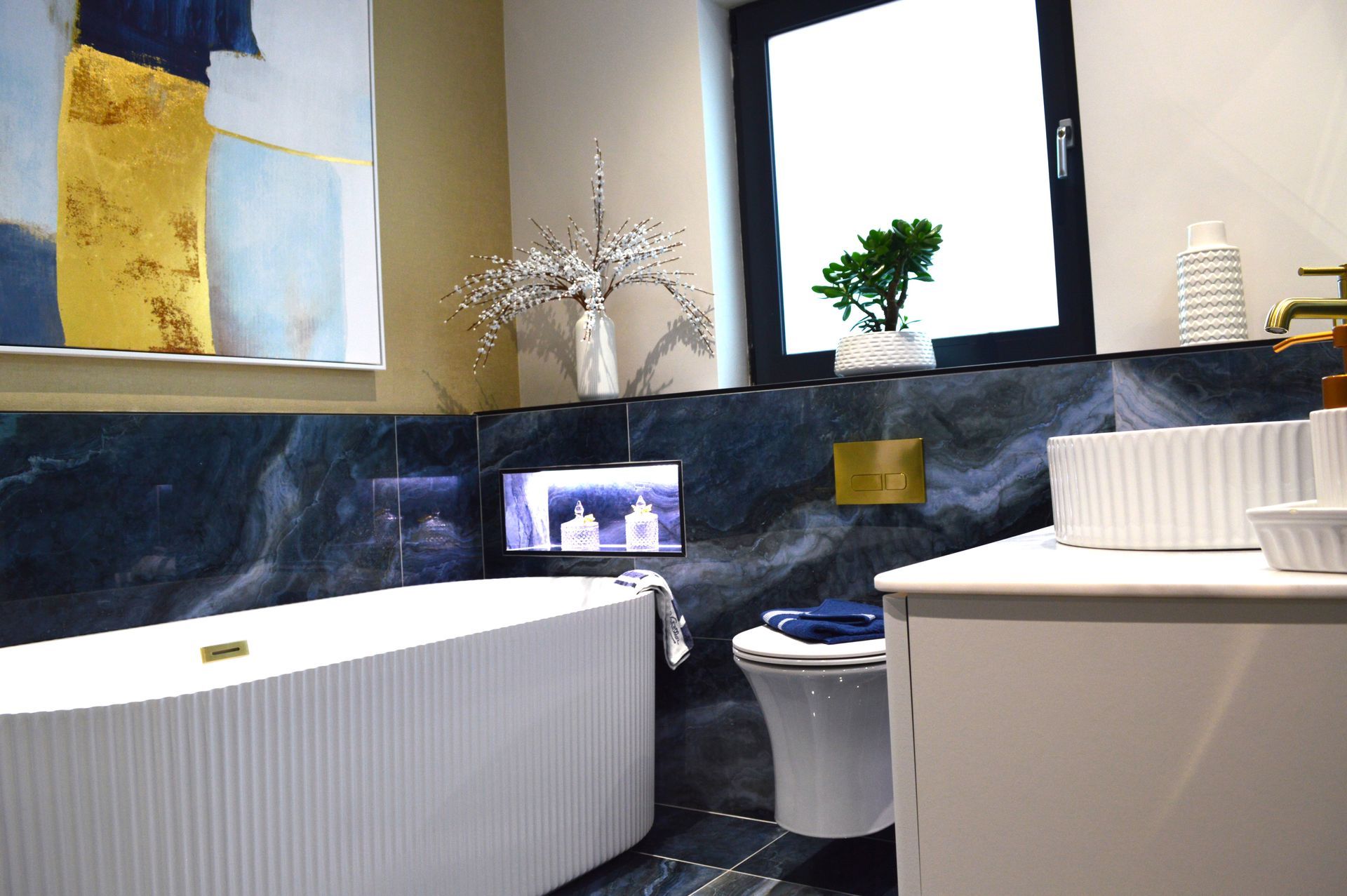 A bathroom with a tub , toilet , sink and window.