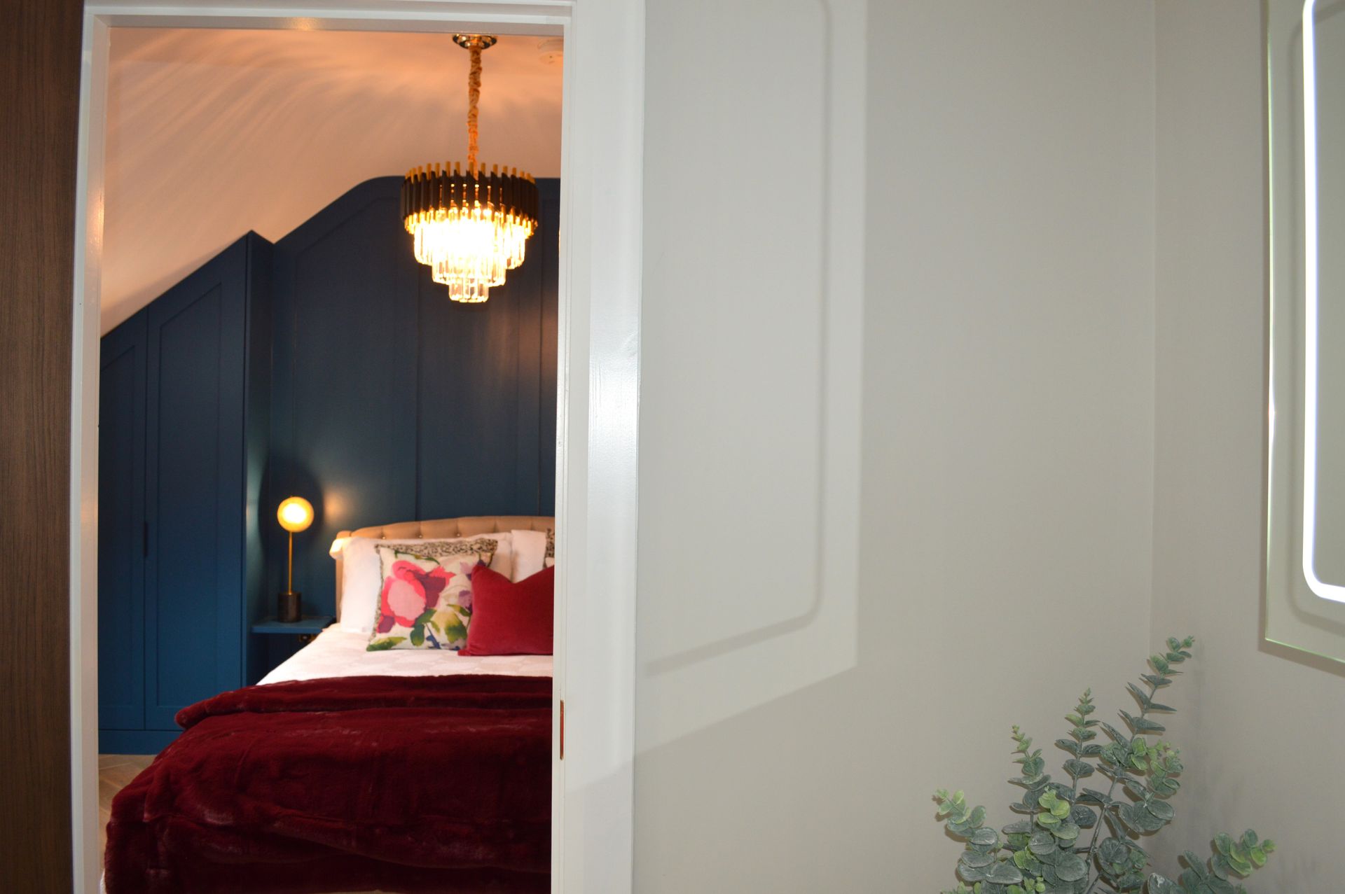 A bedroom with a bed and a window with a chandelier hanging from the ceiling.