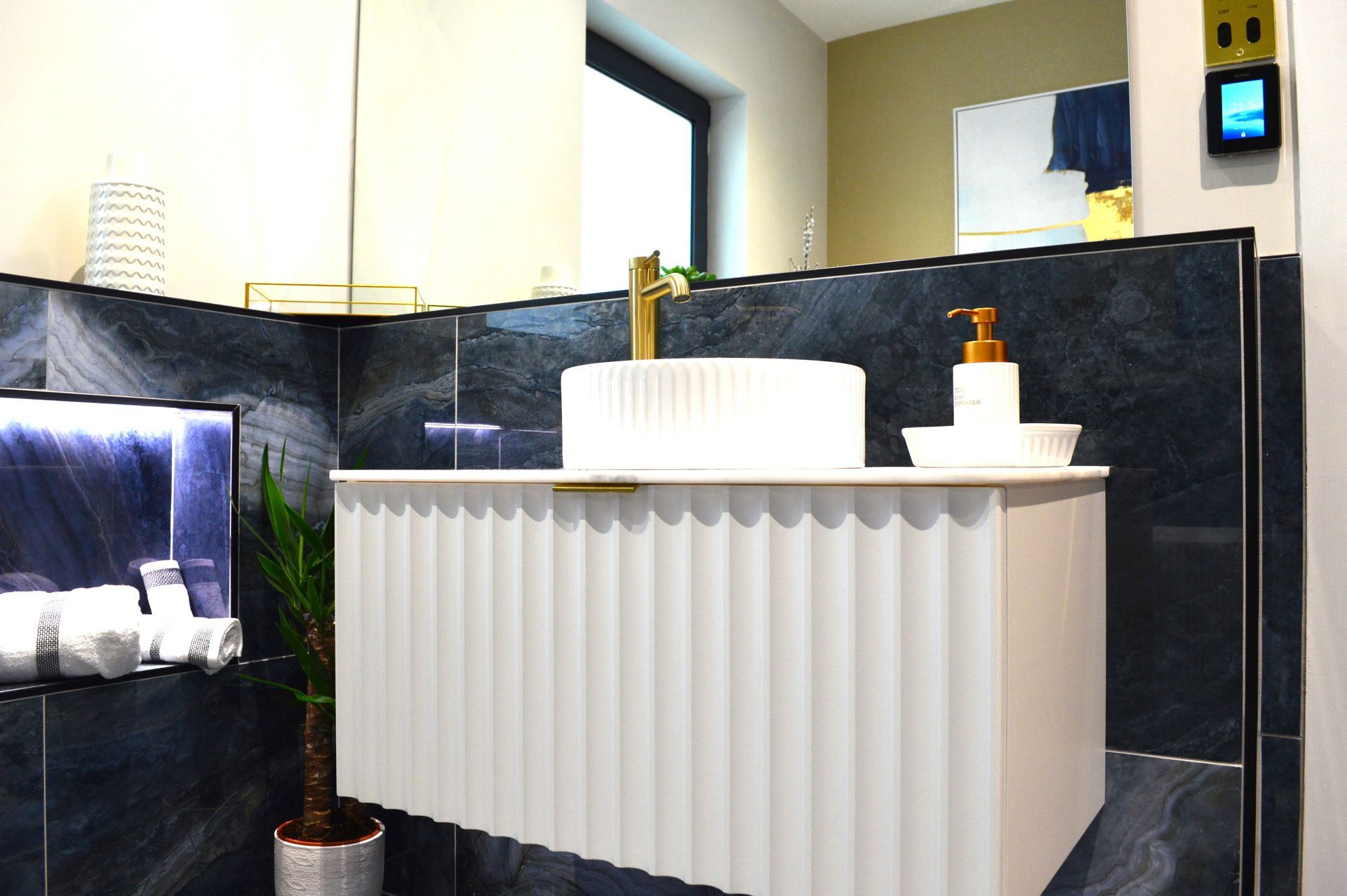 A bathroom with a sink and a thermostat on the wall.