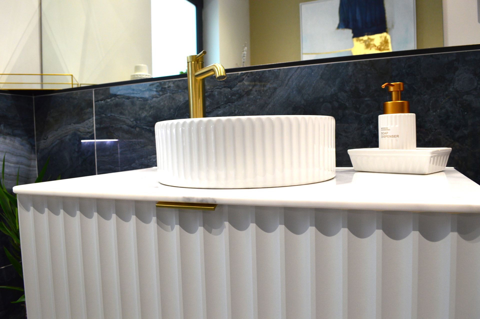 A bathroom with a white sink and a gold faucet.