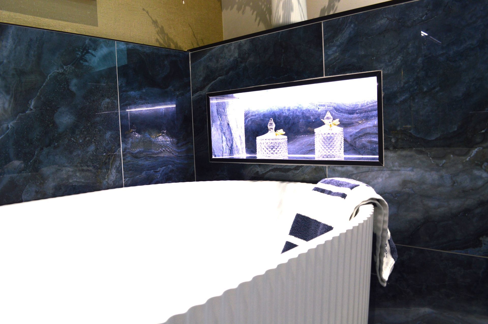 A bathtub in a bathroom with blue tiles on the wall