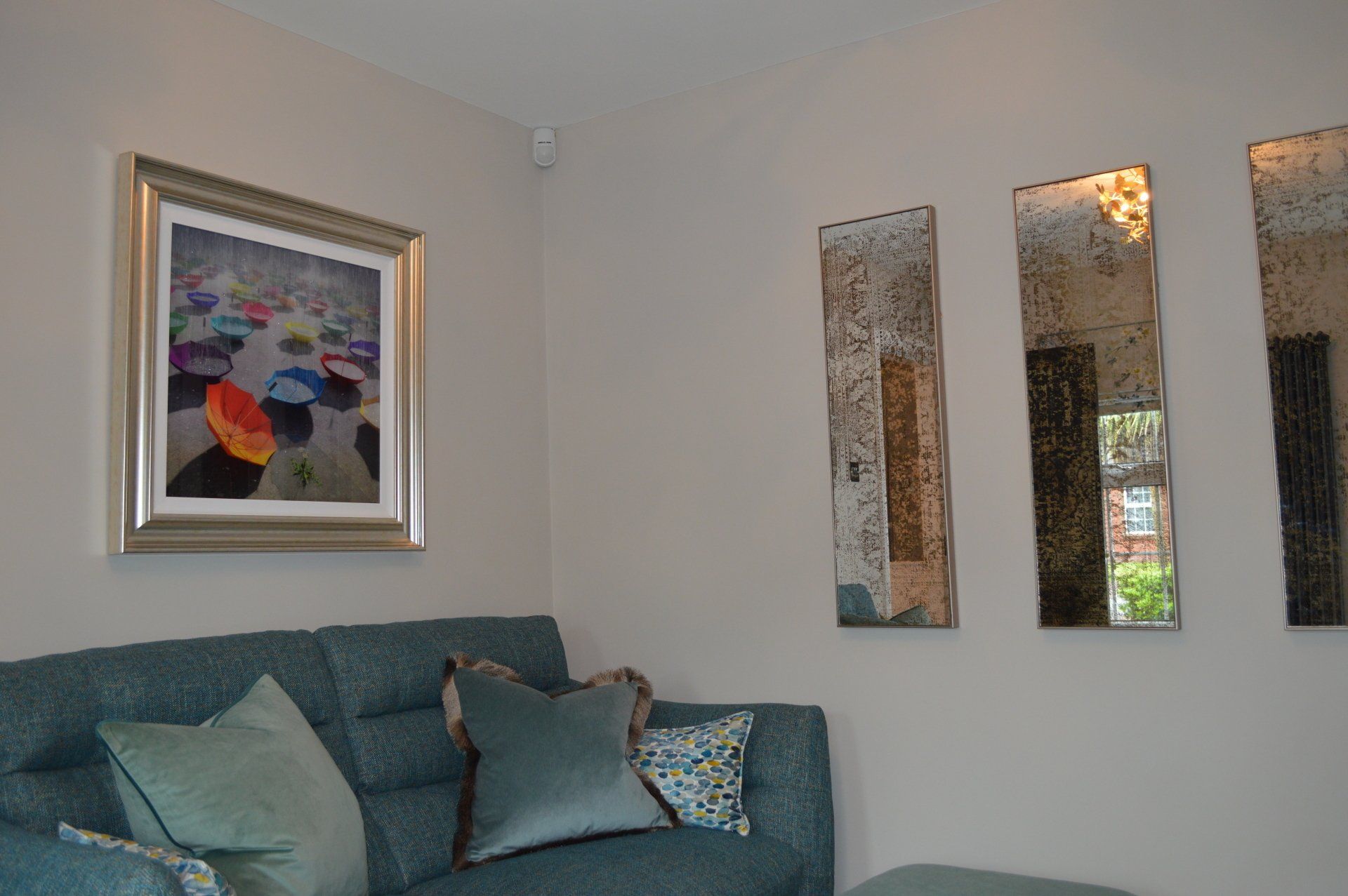 A living room with a blue couch and three mirrors