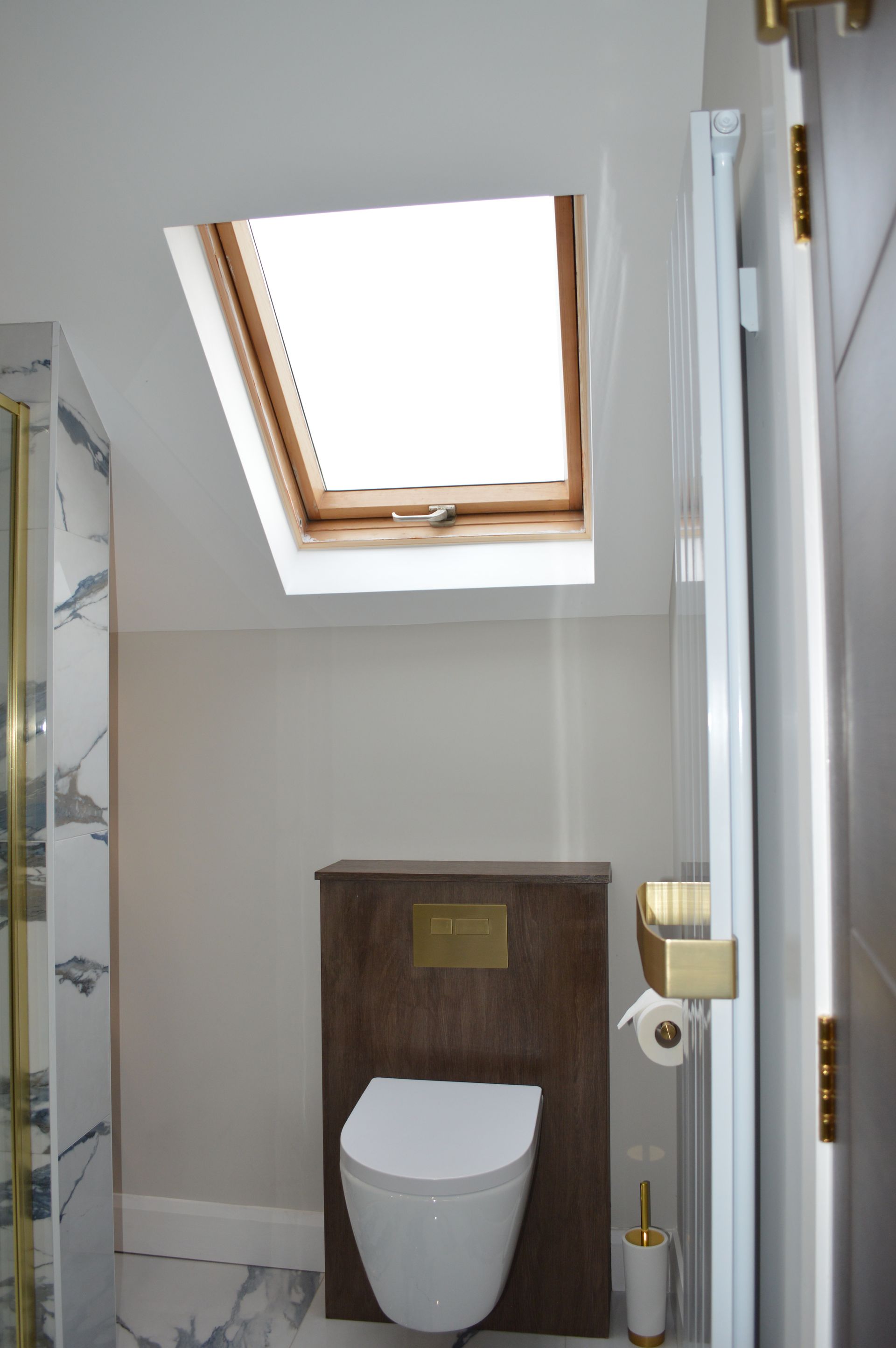 A bathroom with a toilet and a skylight above it