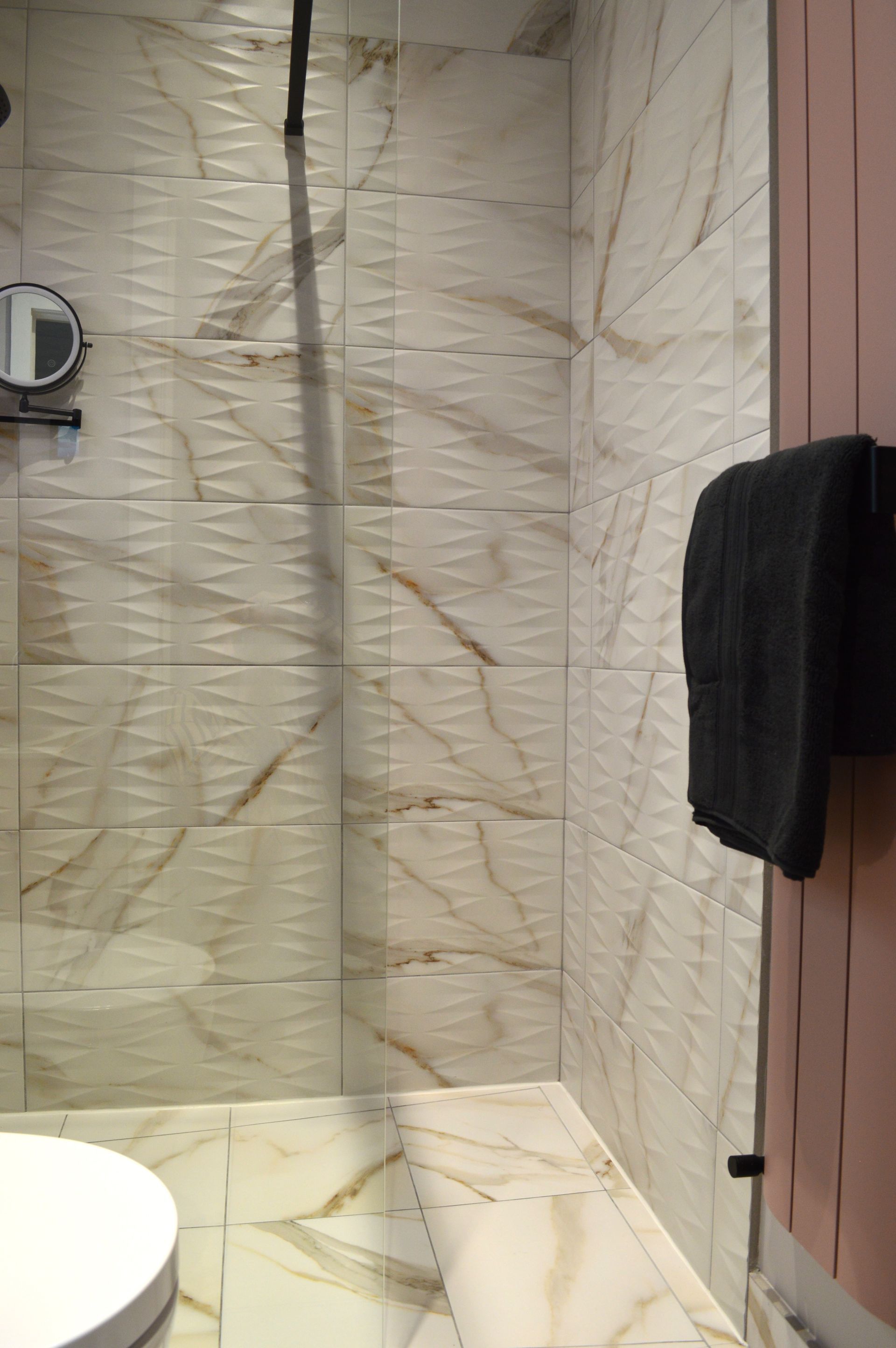 A bathroom with marble tiles and a walk in shower.