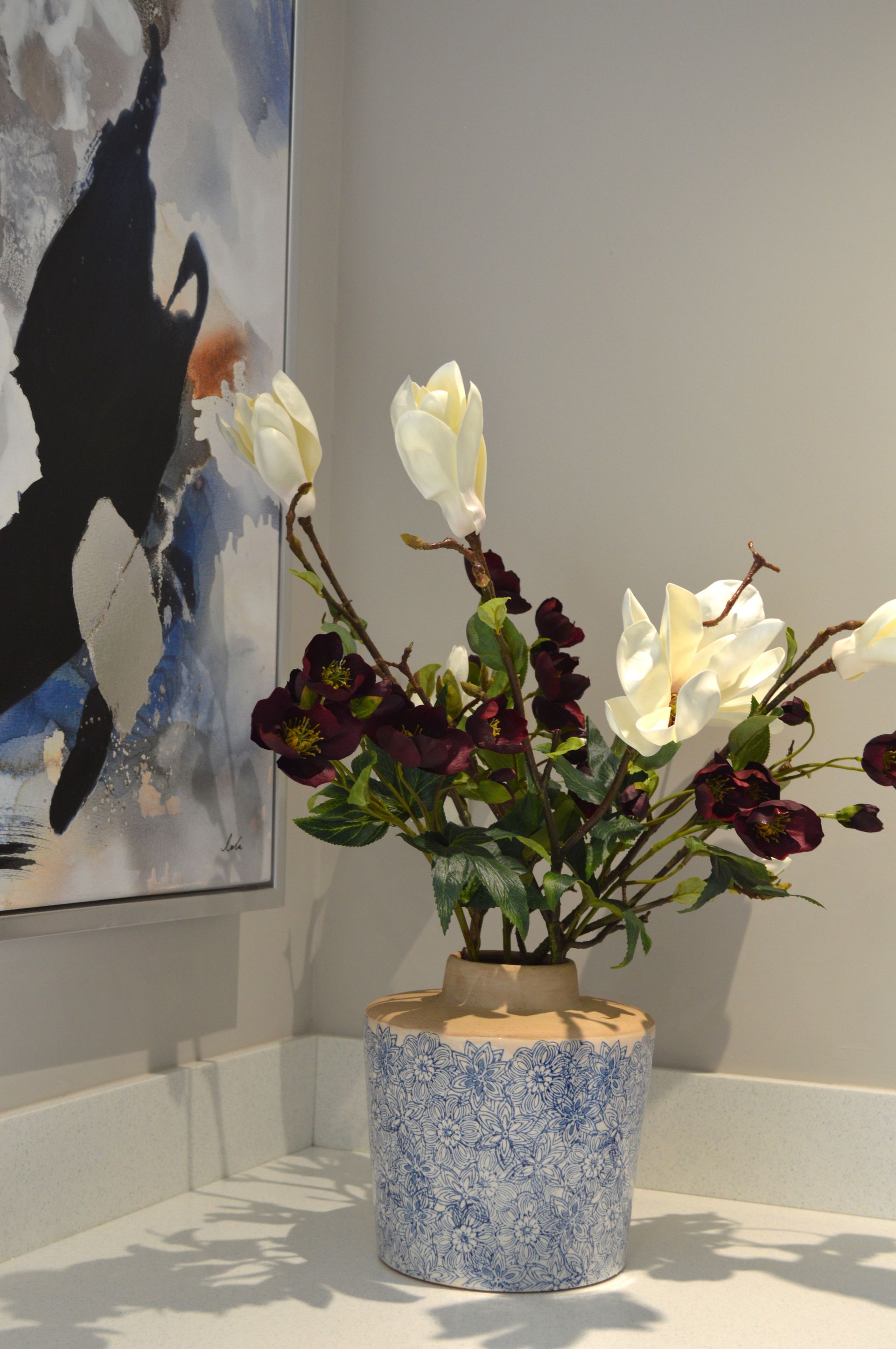 A vase filled with flowers is sitting on a table in front of a painting.