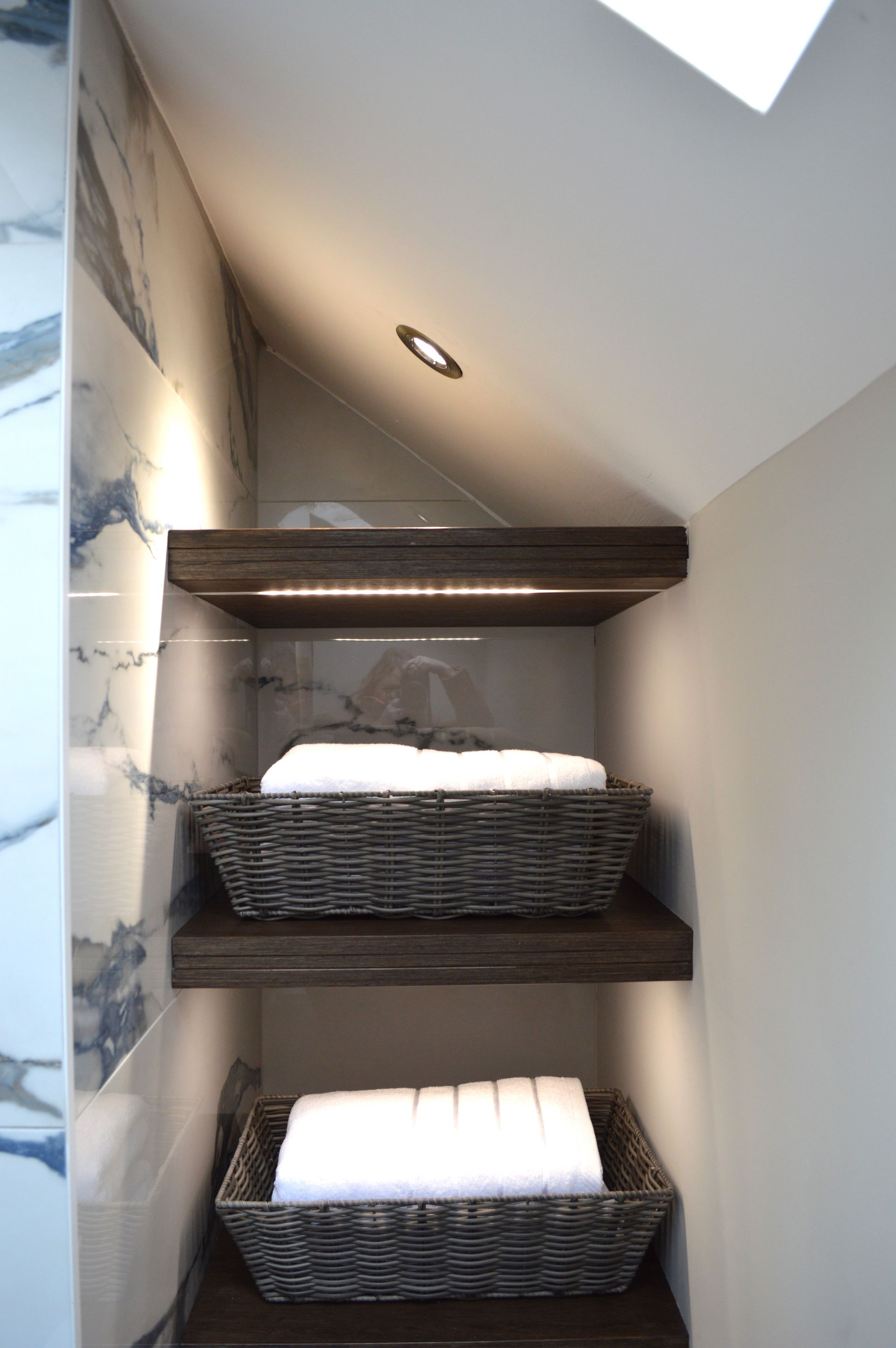 A bathroom with three shelves filled with baskets of towels.