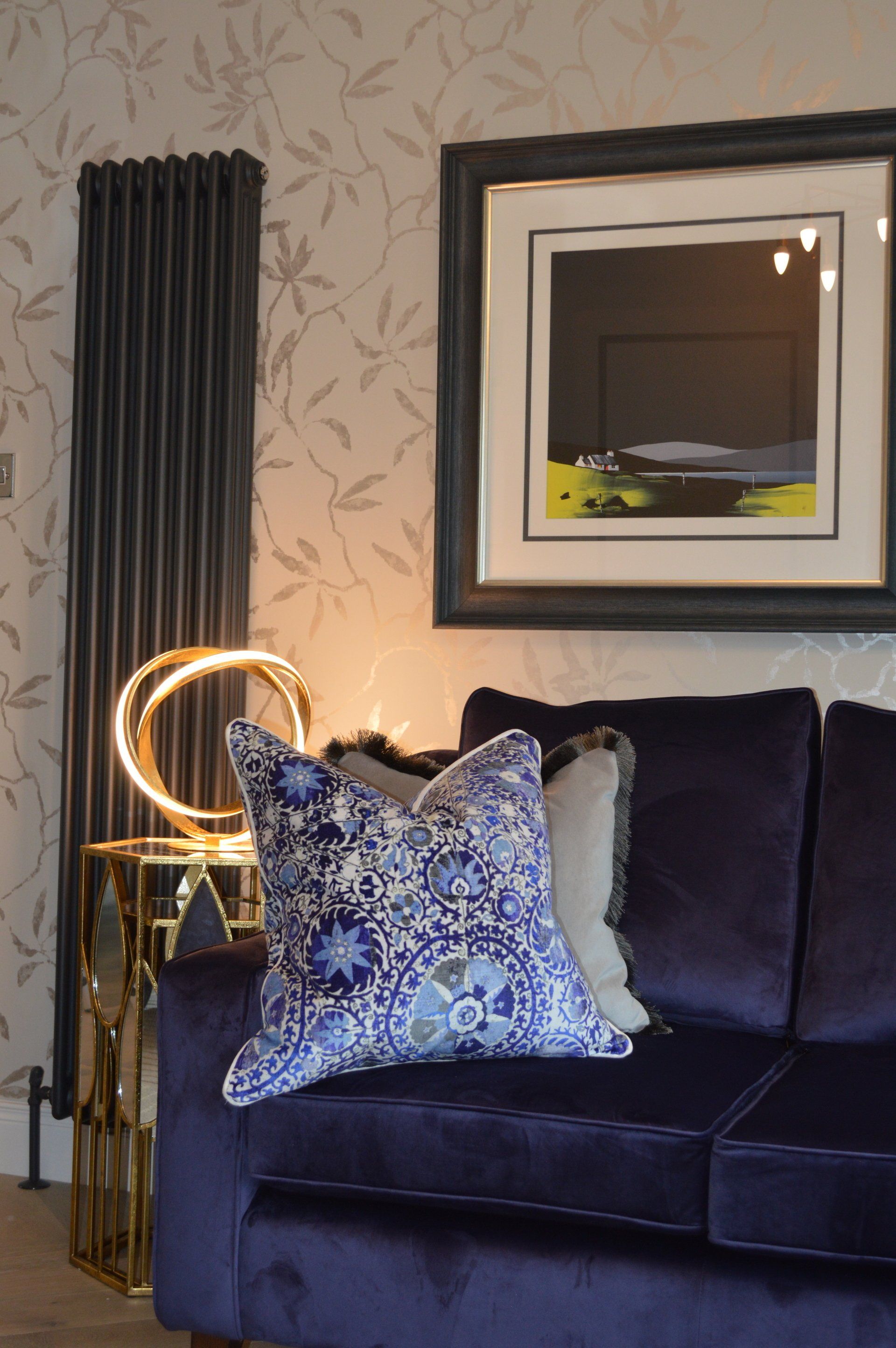 A living room with a purple couch and a picture on the wall.