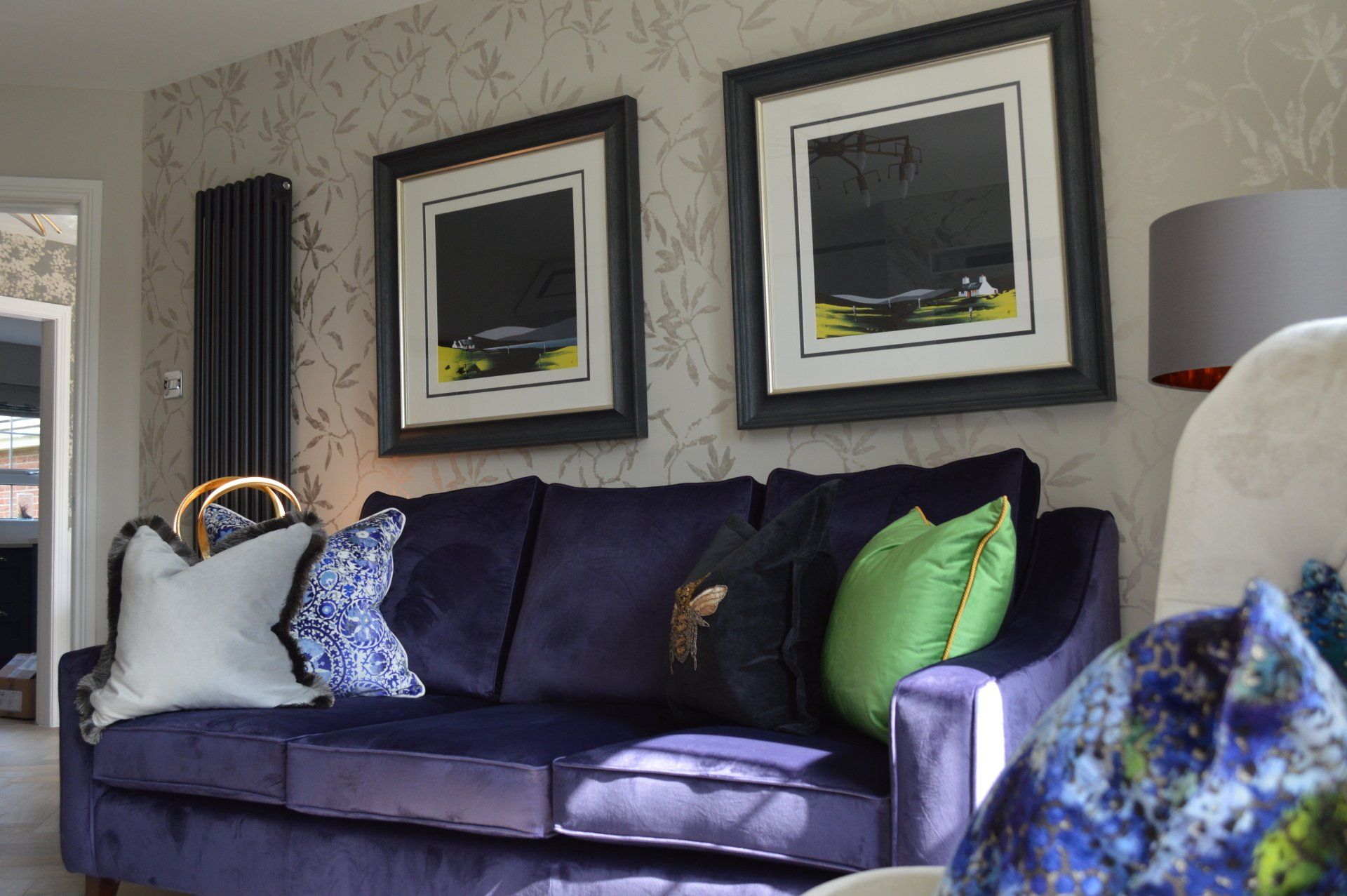 A living room with a purple couch and two framed pictures on the wall.