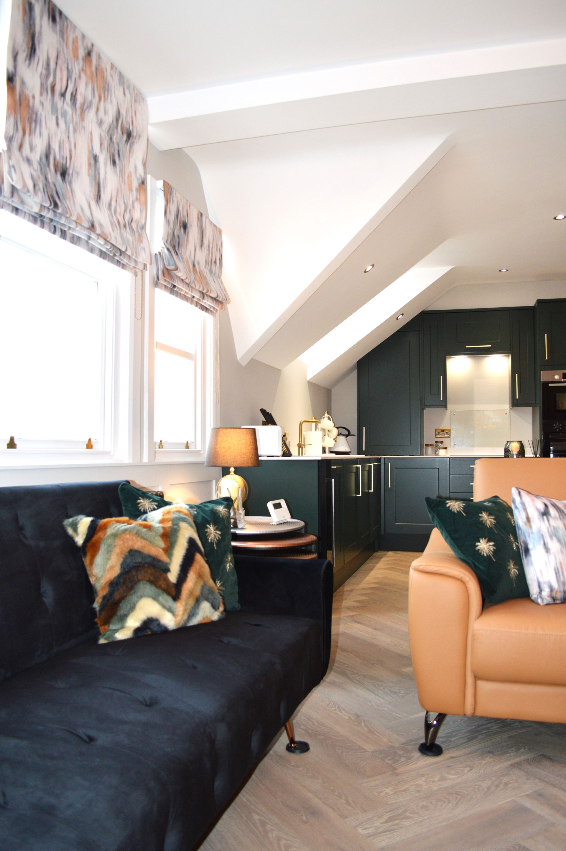 A living room with a black couch and a brown chair
