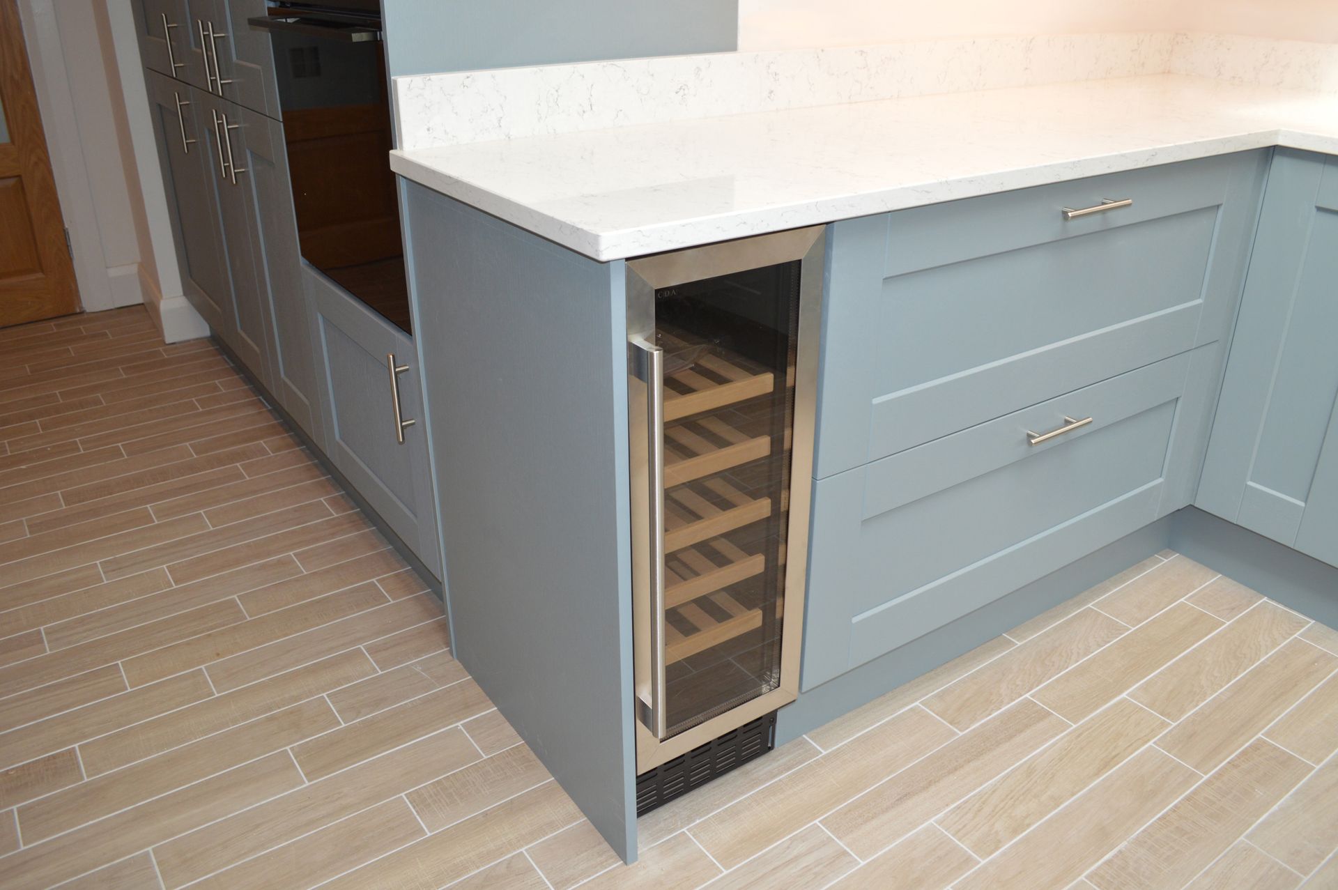 A small wine cooler is built into the corner of a kitchen.