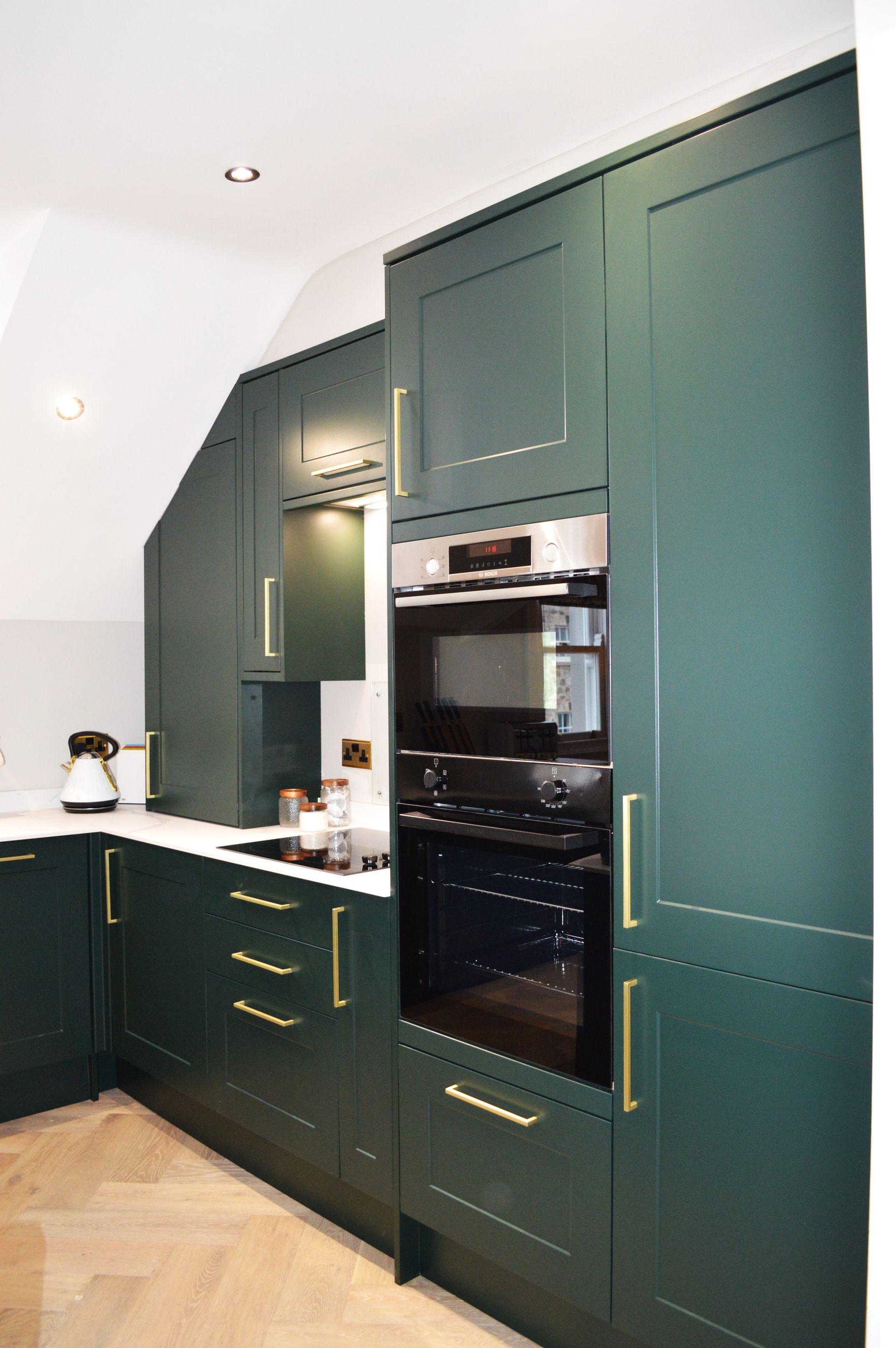 A kitchen with green cabinets and a black oven.