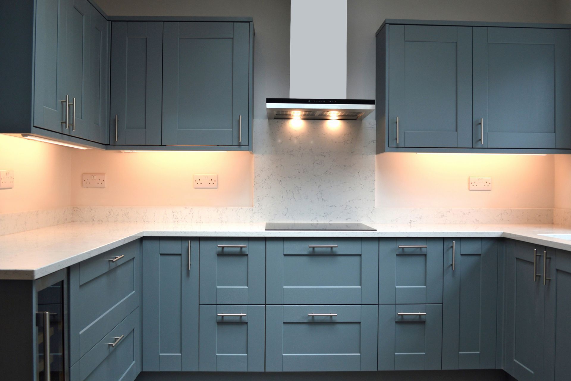 A kitchen with blue cabinets and white counter tops