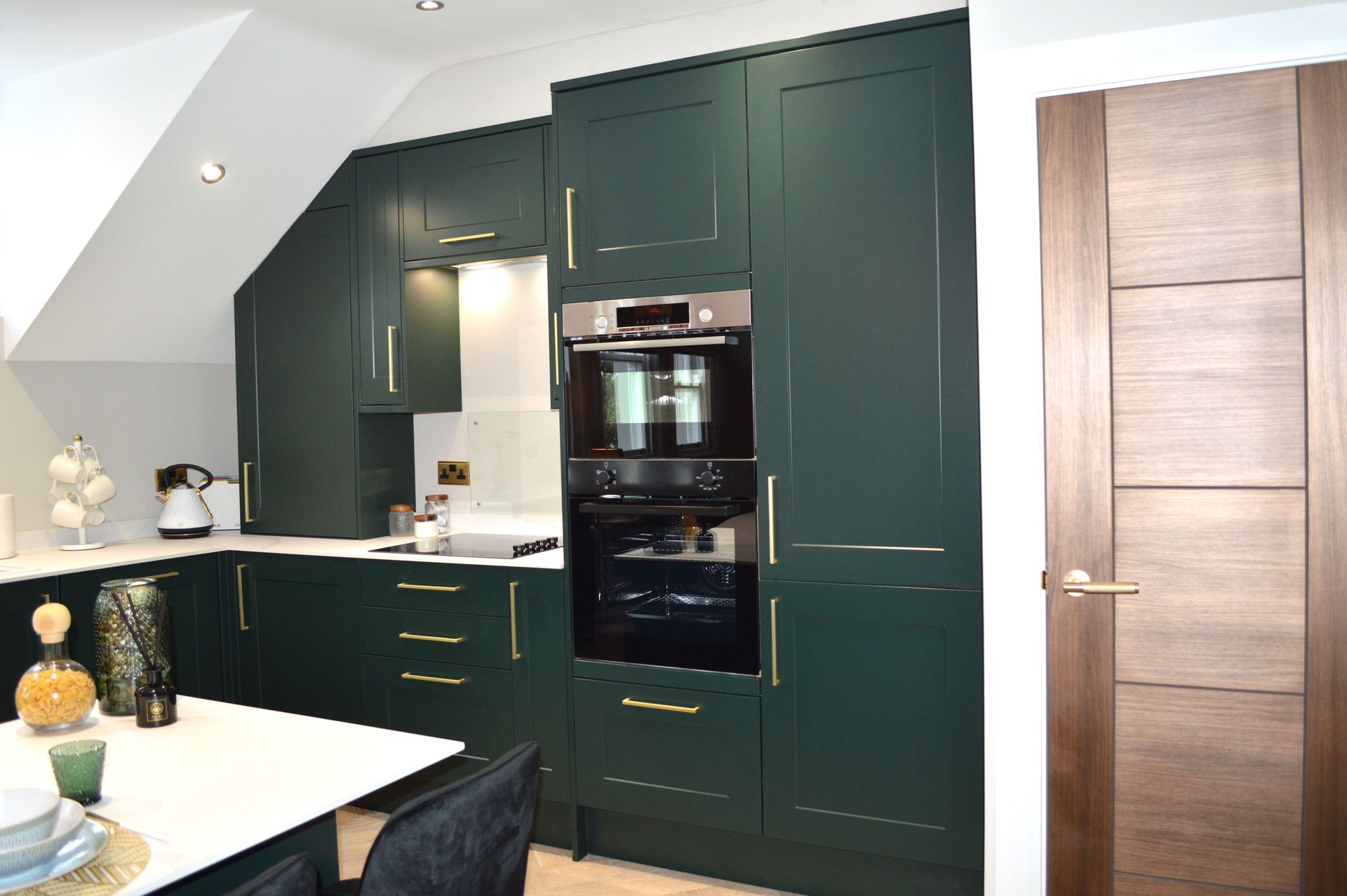 A kitchen with green cabinets and a black oven.