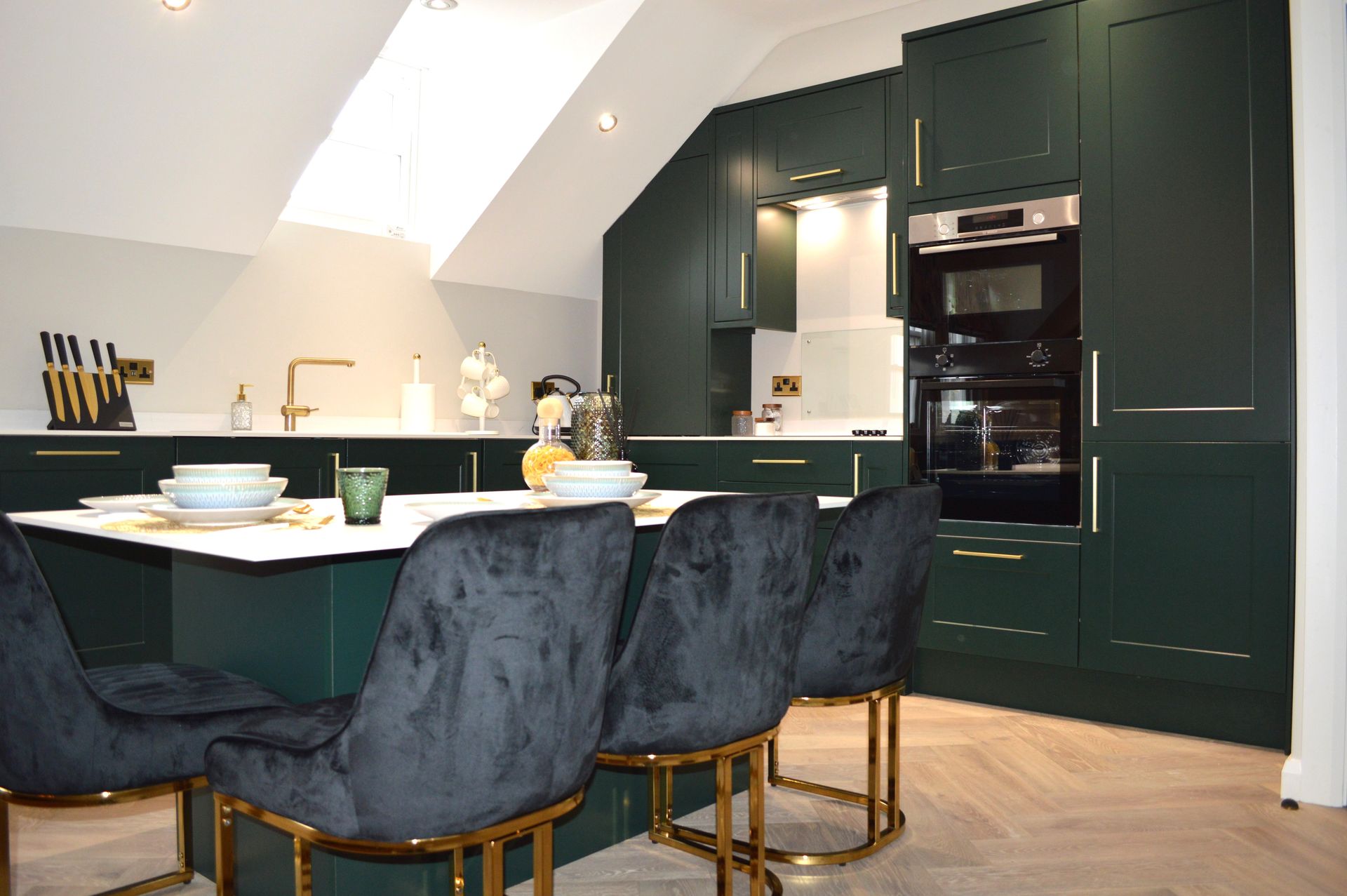 A kitchen with green cabinets and black chairs and a table.