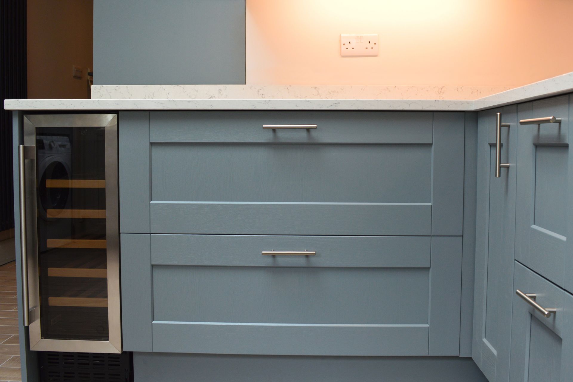 A kitchen with blue cabinets and a wine cooler.