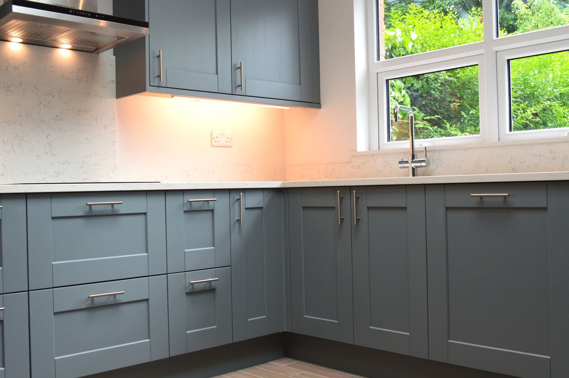 A kitchen with gray cabinets and a large window