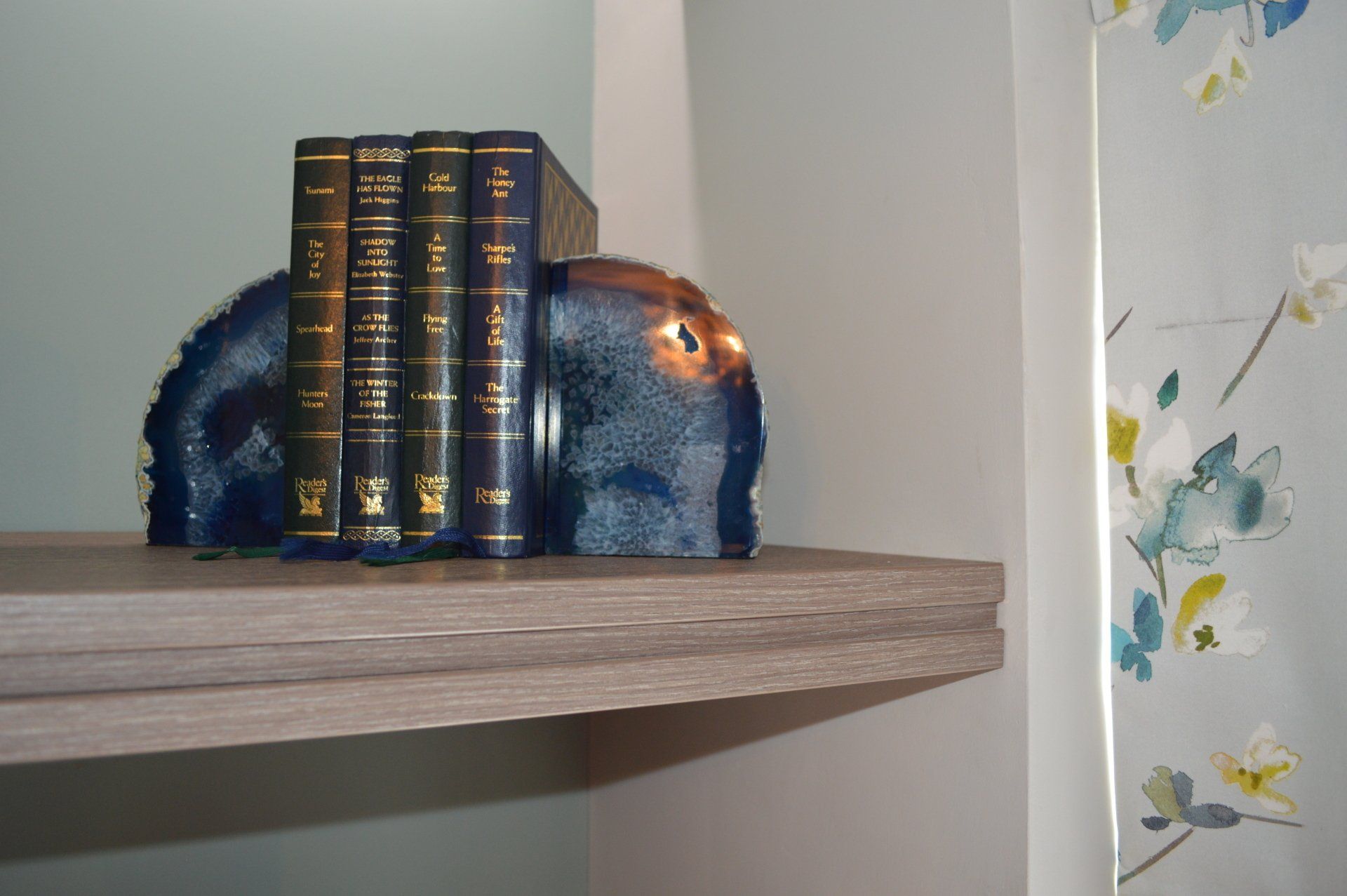 Three books are sitting on a shelf next to a statue of an elephant.