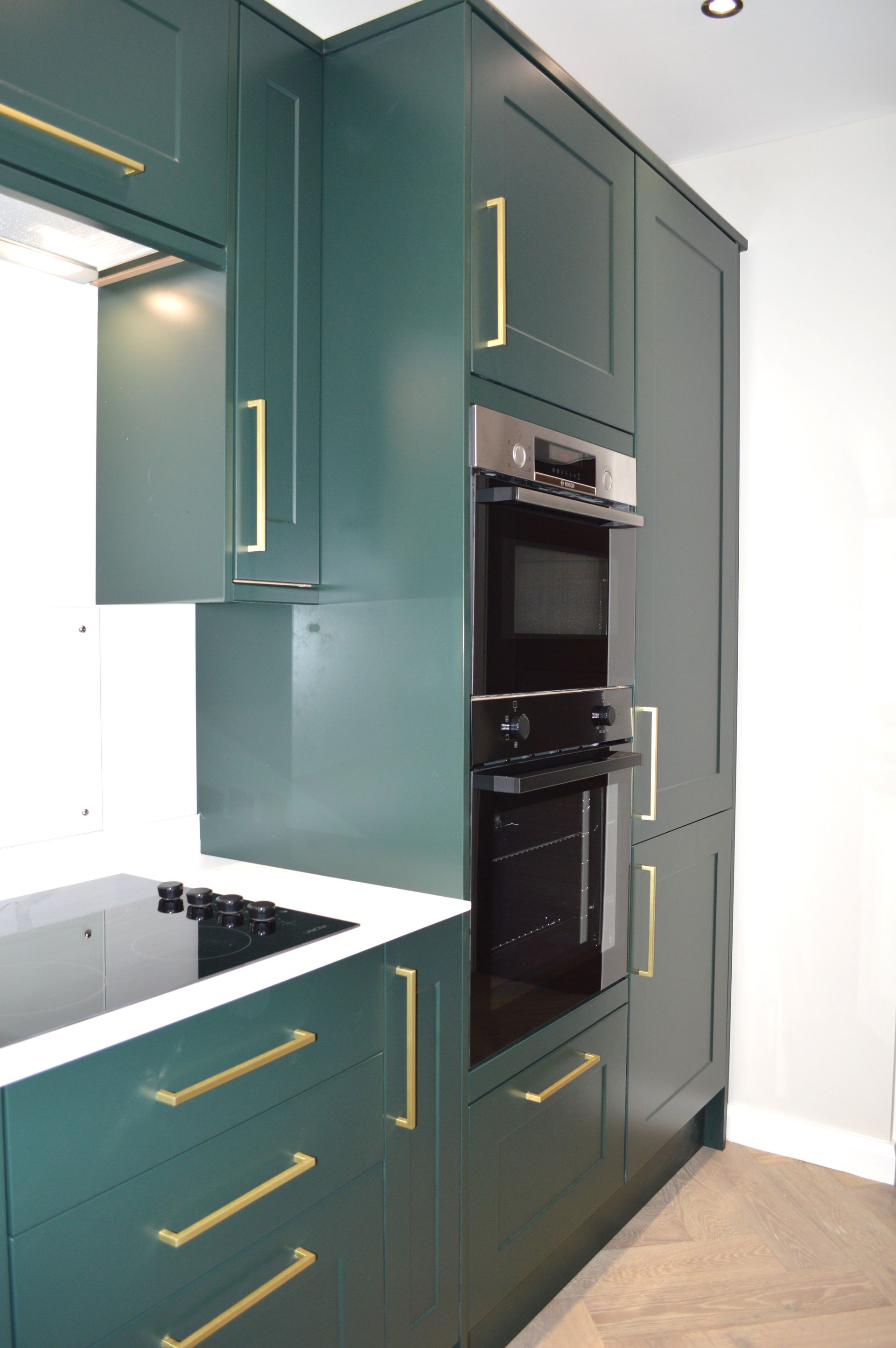 A kitchen with green cabinets and gold handles and a stove.